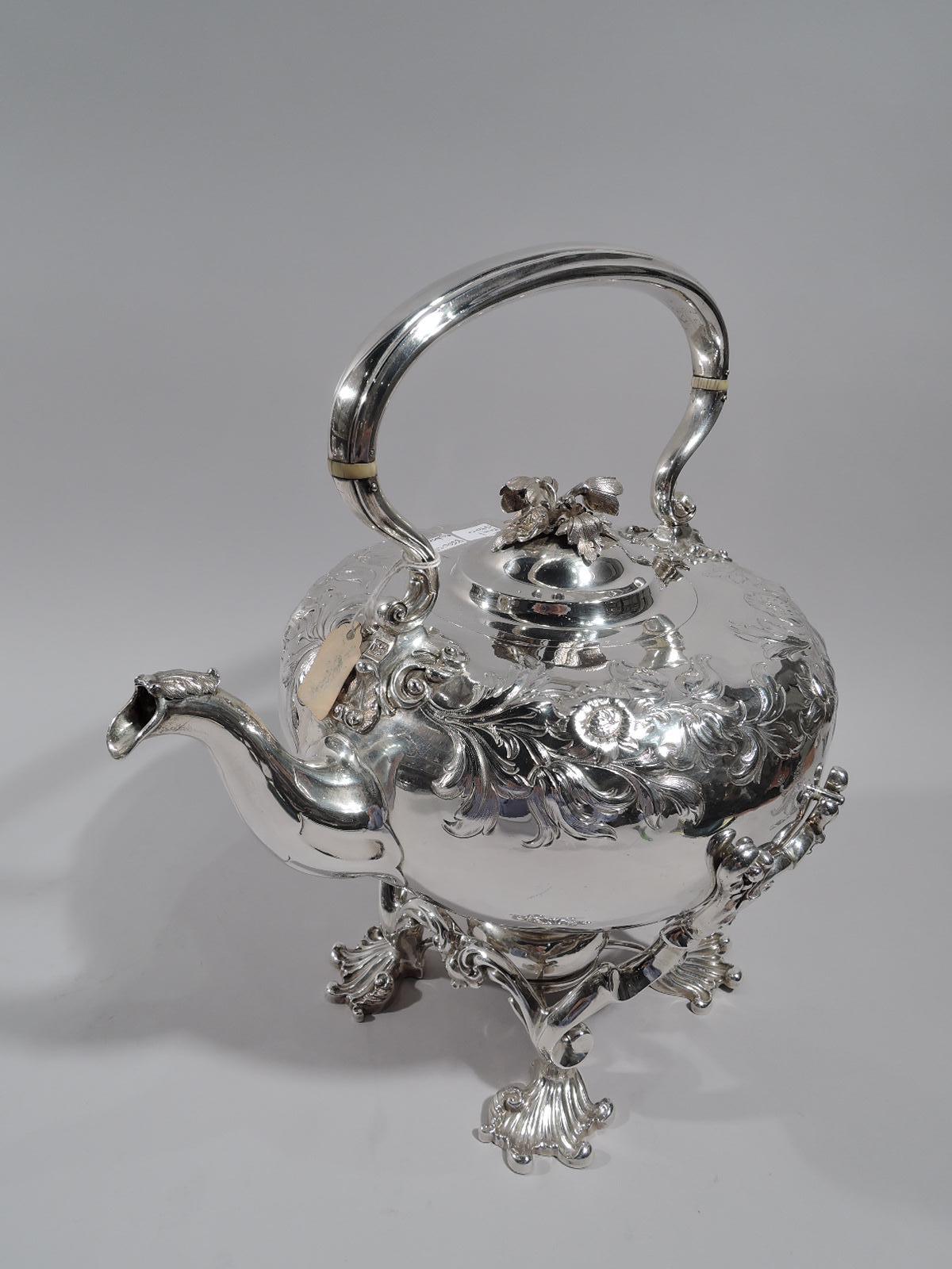 William IV sterling silver hot water kettle on stand. Made by Paul Storr in London in 1837. Kettle: Round with c-scroll stationary handle with leaf and scroll mounts, hinged and domed dome cover with flower finial, and leaf-capped spout. Chased