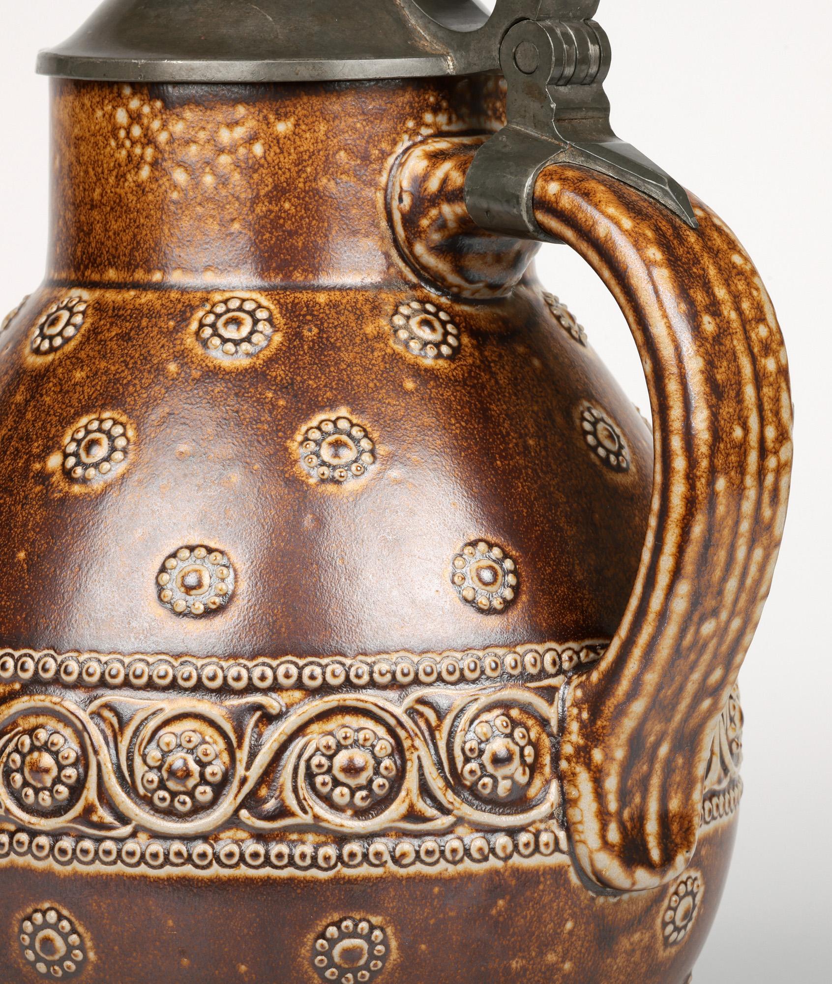 Un'elegante brocca in ceramica con montatura in peltro di Paul Merkelbach (1879-1956), risalente al 1905 circa. La grande brocca in gres poggia su una stretta base piatta e rotonda non smaltata ed è di forma rotonda e bulbosa con uno stretto e corto