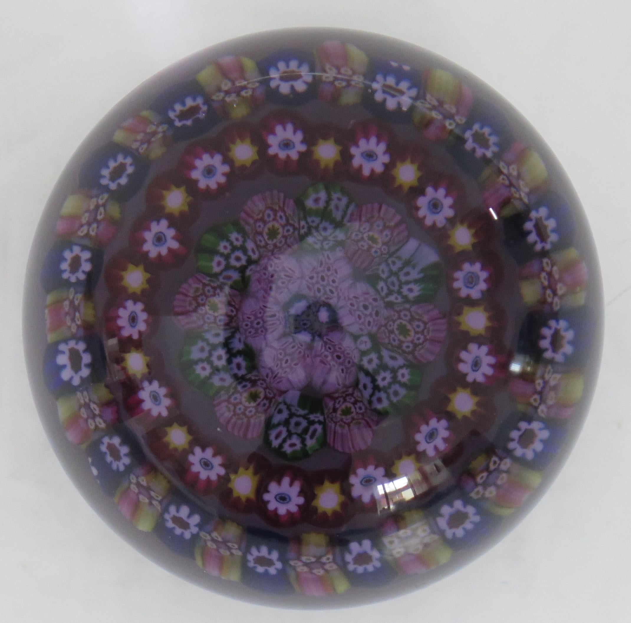 This is a beautiful handmade concentric Millefiori, PY cane, Dark Glass Paperweight made by Paul Ysart in Scotland, during his early period, Circa 1930s.

The canes are arranged as two open concentric rings around a six spoke tightly packed centre