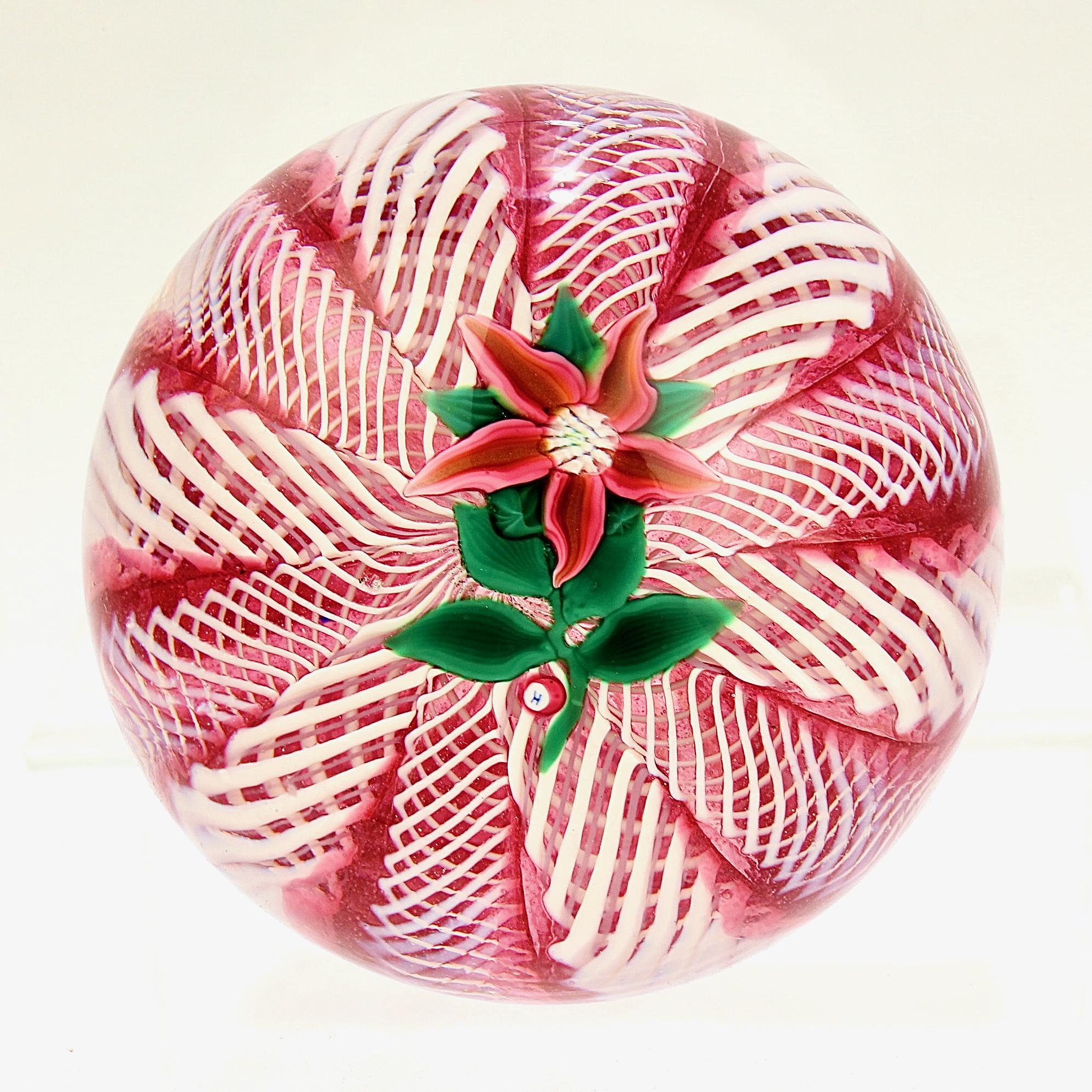 A fine Paul Ysart glass paperweight.

It has a slightly off-center poinsettia flower on a pink and white latticinio ground.

It has an H cane for Harland Glass Studios below the flower.

Simply a wonderful paperwieght!

Date:
20th century

Overall