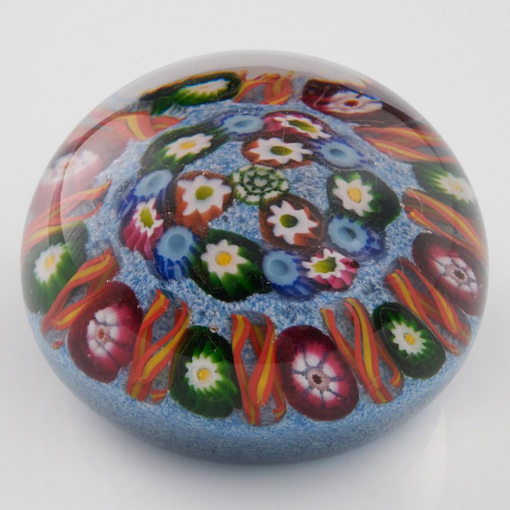 Heading : A Paul Ysart Ten Spoke Radial Millefiori Paperweight c1950
Date : c1950
Origin : Scotland
Features : Ten radial twists interspersed with a single cane around a two row millefiori concentric centre on a light blue mottle ground
Marks :
