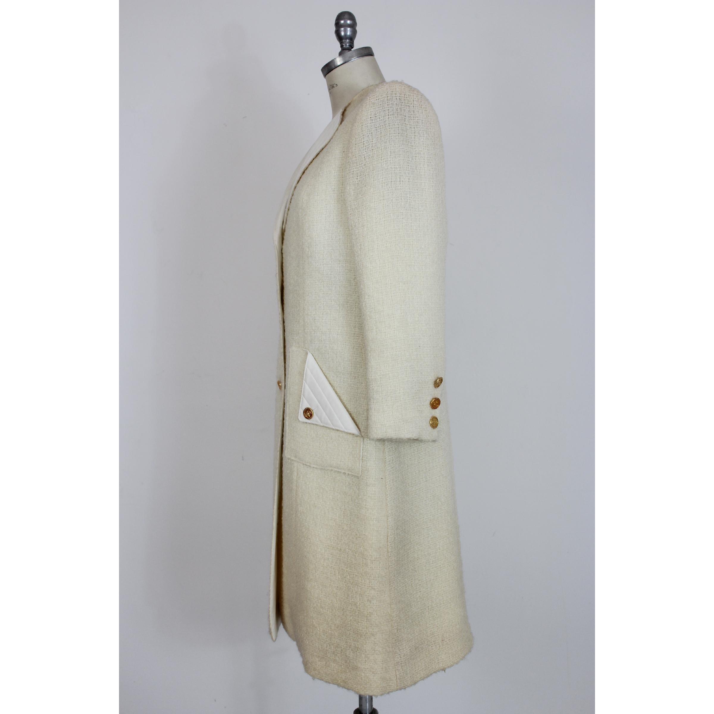 Manteau femme vintage des années 80 Paula Klein, modèle long, blanc, 100% pure laine avec col et poches en matelasse. Fermeture par boutons dorés, intérieur doublé. Fabriqué en France. Très bon état vintage, avec quelques petites taches qui ne