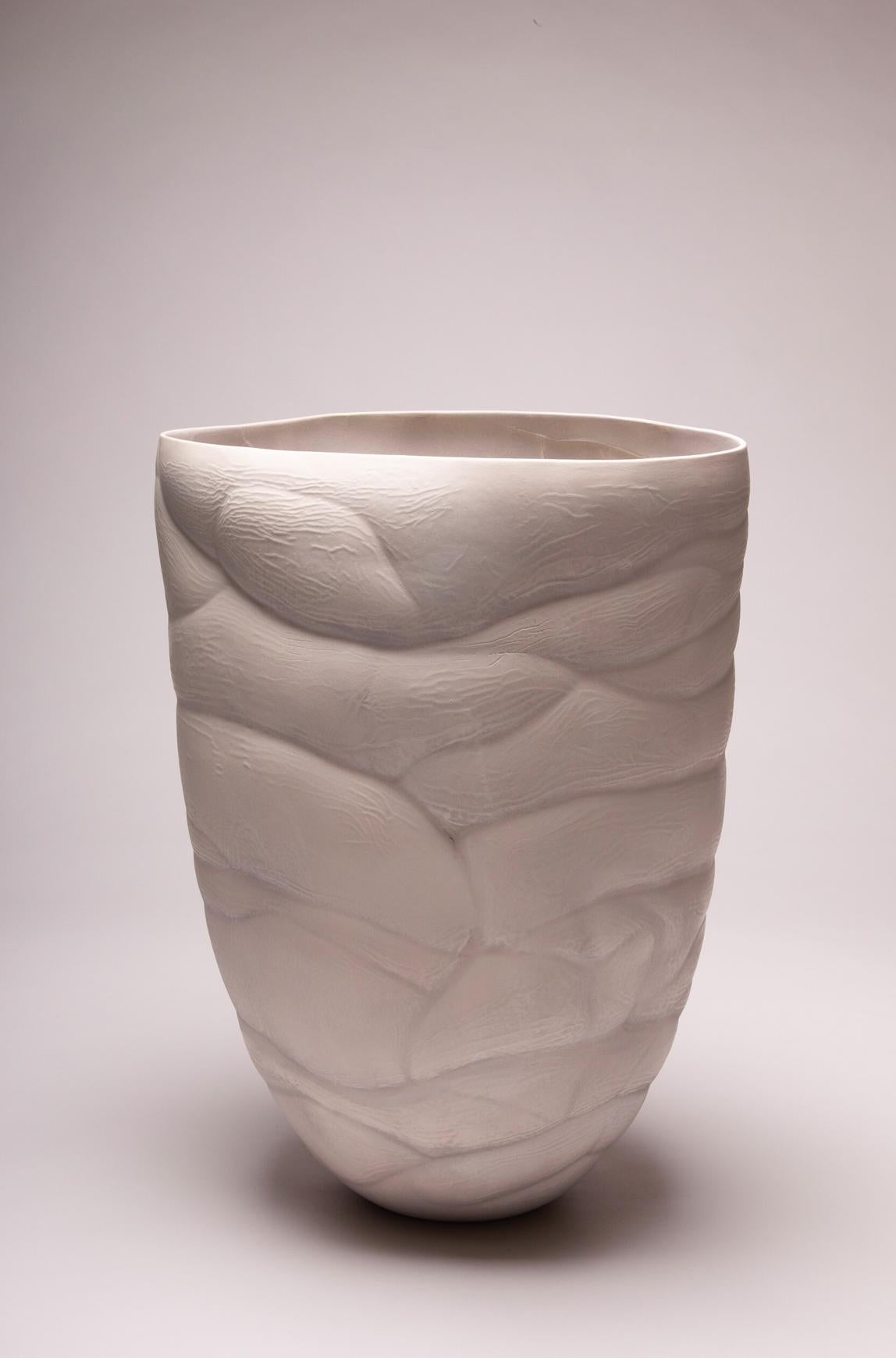 In her lakeside studio surrounded by nature, Paula Murray creates uniquely beautiful porcelain pieces. This creamy white vessel has a tall undulating form. Wave-like patterns that run both outside and inside the piece accentuate its elegant