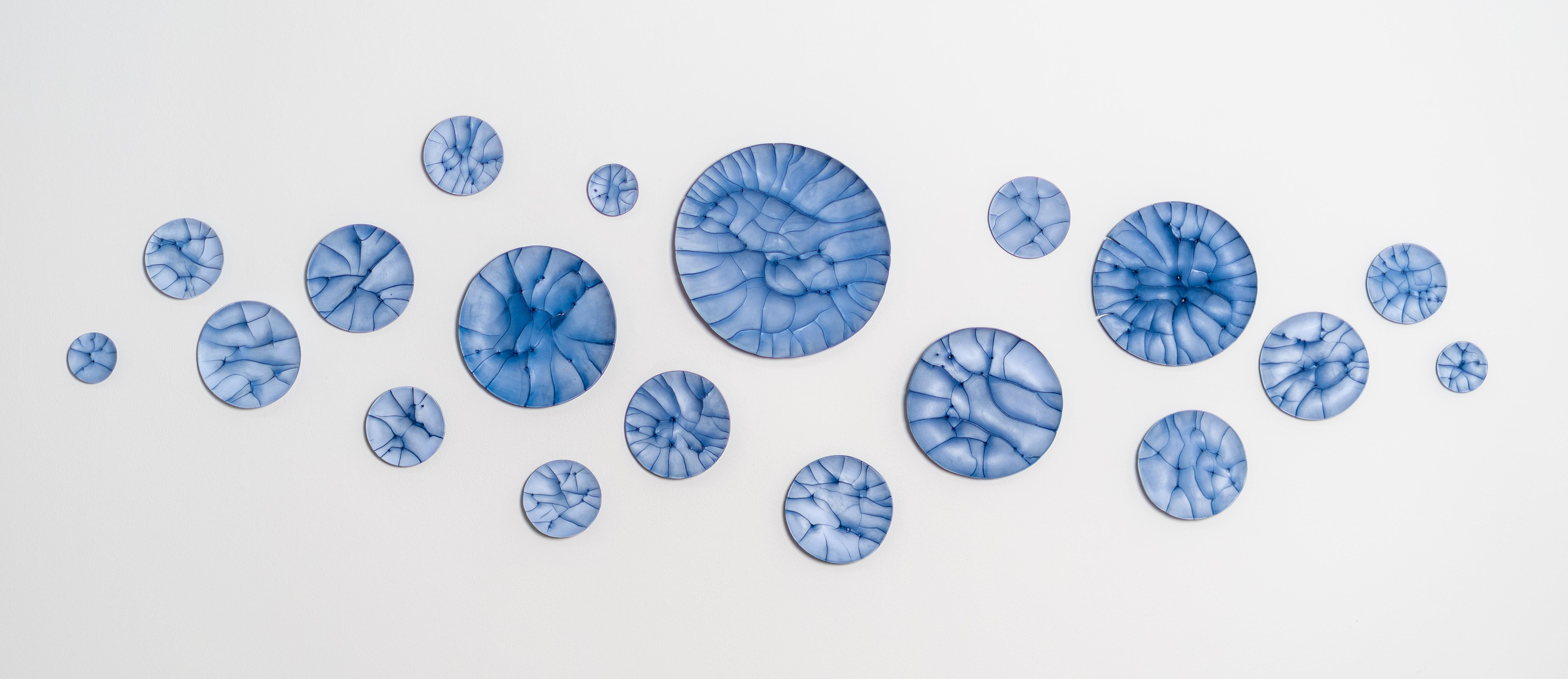 This contemporary horizontal wall composition by Paula Murray is composed of blue porcelain discs.
 
An internationally recognized and collected artist, Paula Murray’s sublime work in clay is highly valued for its original, organic design and