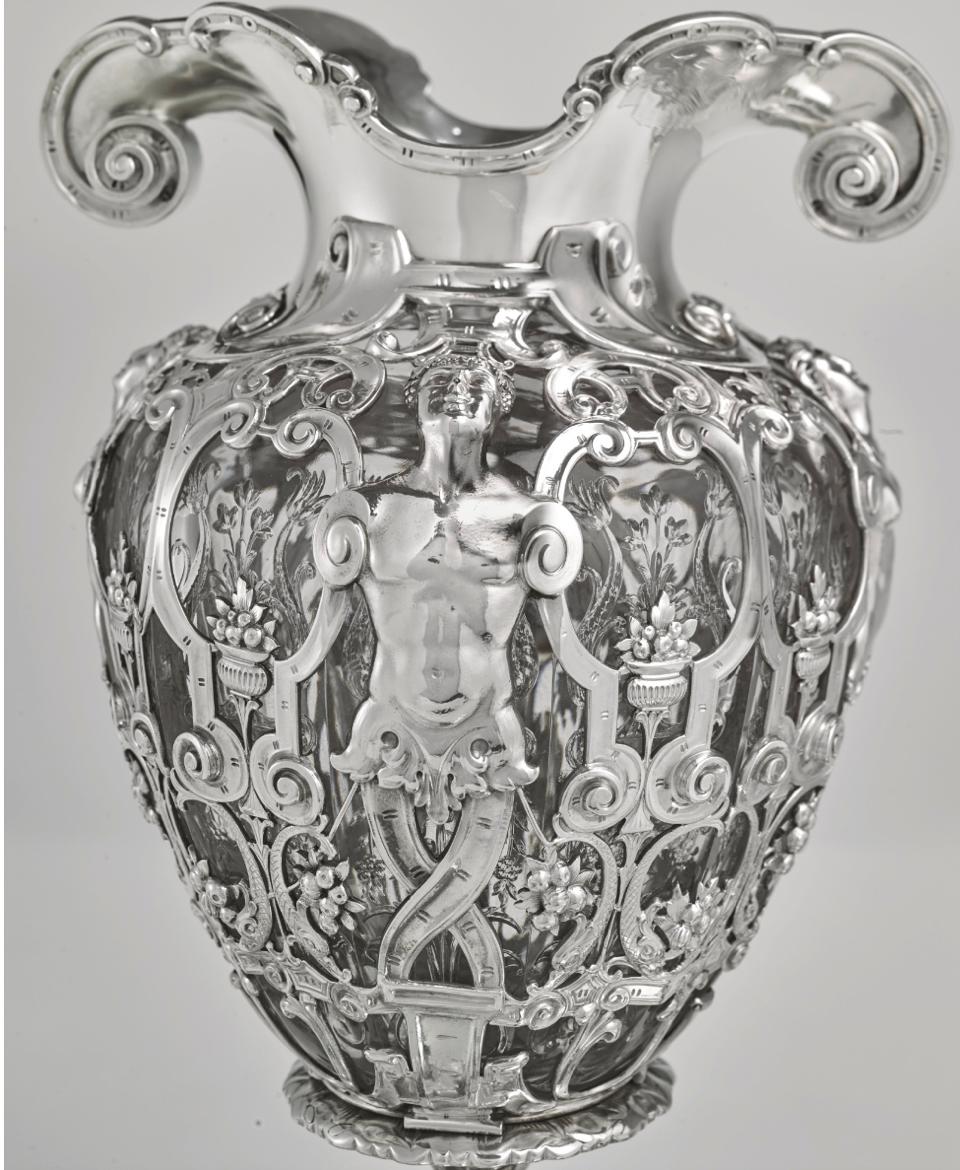 Paulding Farnham for Tiffany & Co., New York, circa 1905

Silver and cut-glass Renaissance Revival pattern centerpiece mounted on a mirror plateau, the openwork base hung with fruit swags and centered by a cartouche on each side engraved with