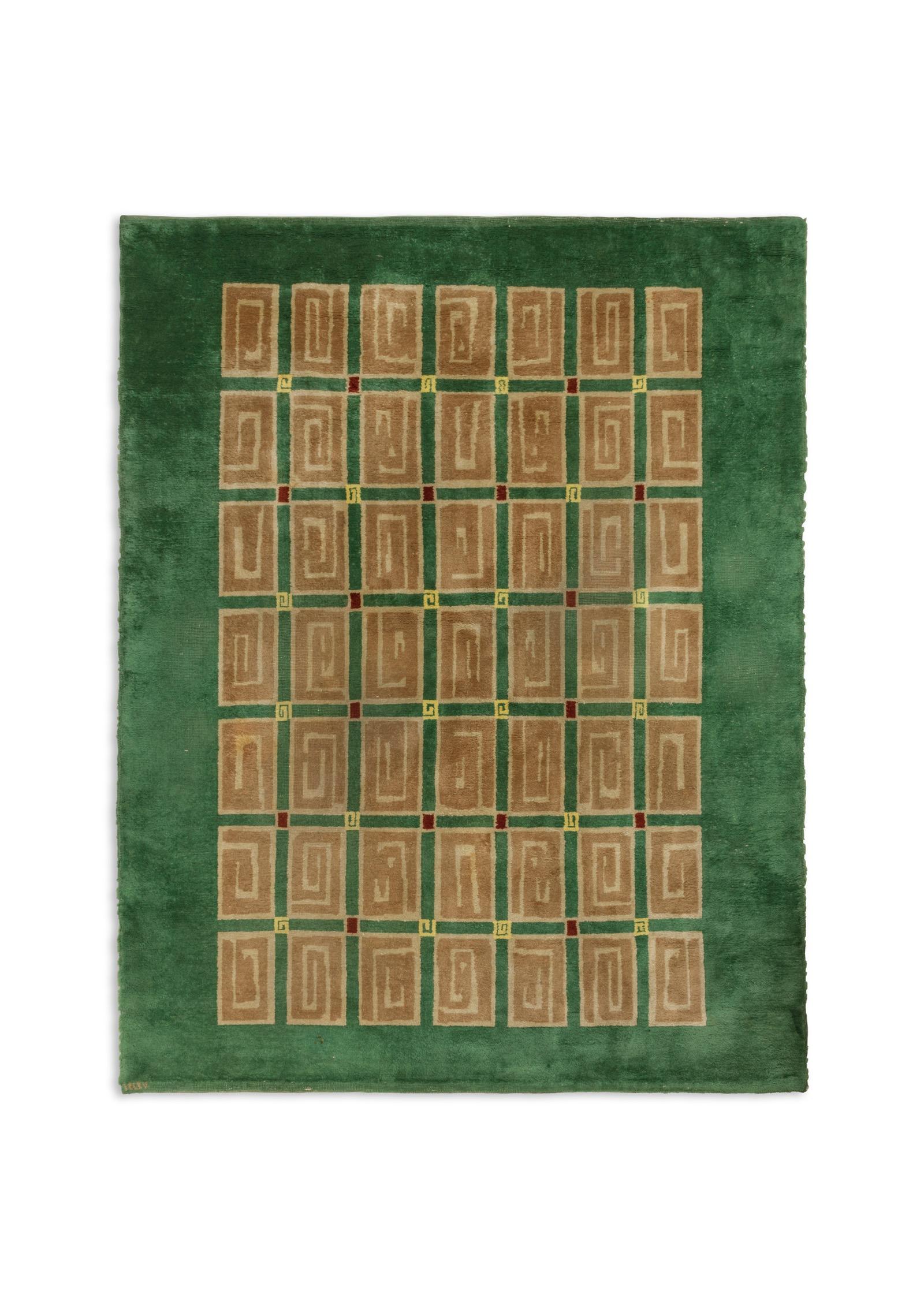 A rectangular knotted woollen rug with stylized beige scrolls on a green background. Signed in the frame.