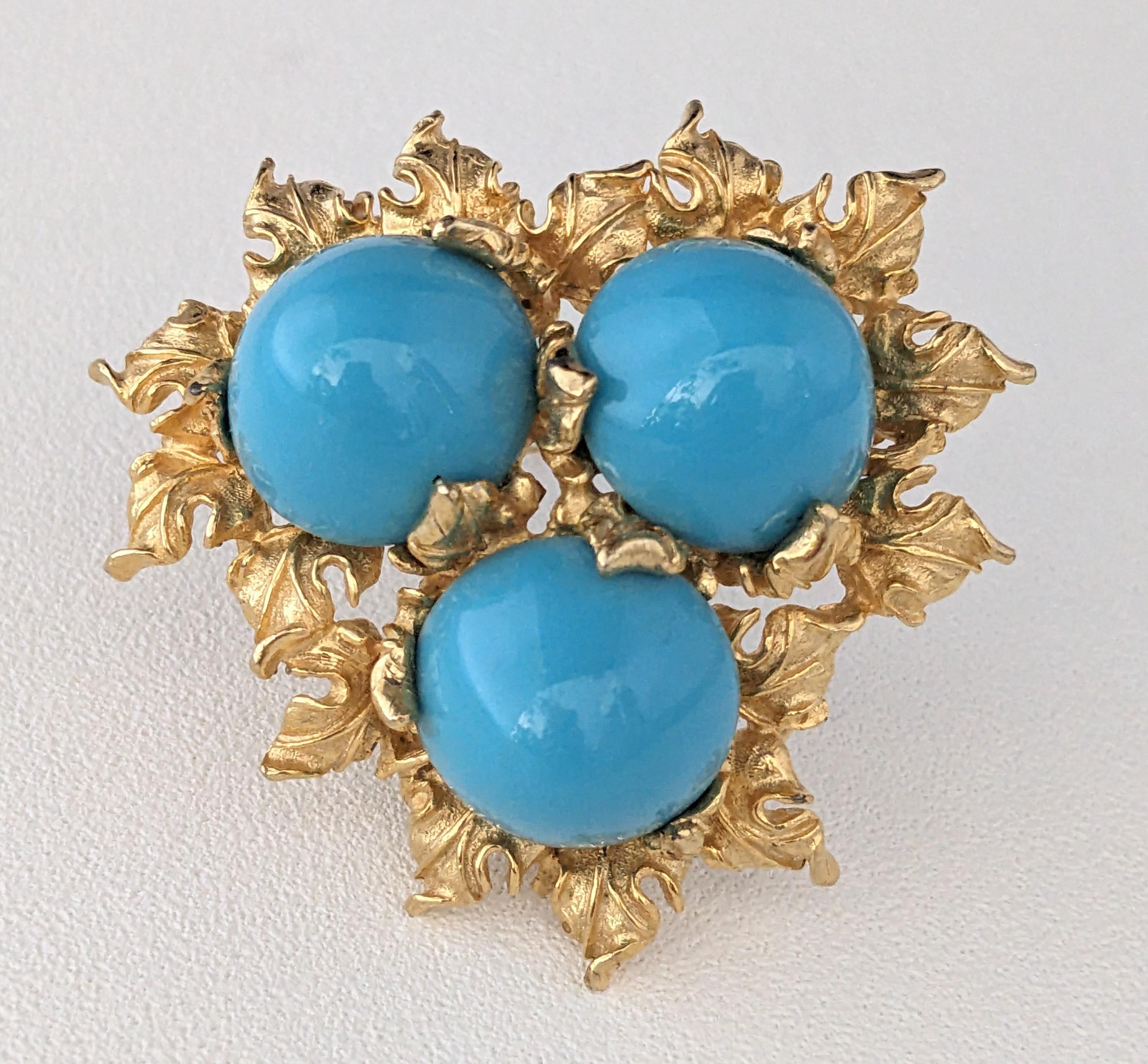 Atractivo broche de cabritilla turquesa Pauline Rader de la década de 1960. Grandes cabujones de turquesa de imitación están anidados en un rico marco con motivos de hojas doradas. 2.25