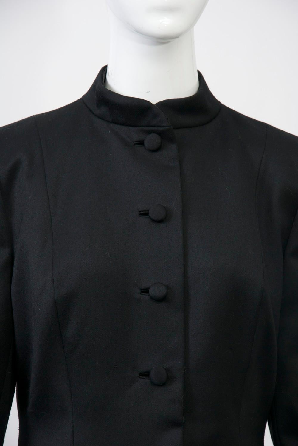 Stunning jacket by Pauline Trigère, c.1970s, in black smooth wool featuring a deep black fox border at the hem. Single breasted with self buttons and bound buttonholes, a shallow mandarin collar, and body hugging profile complete the elegant