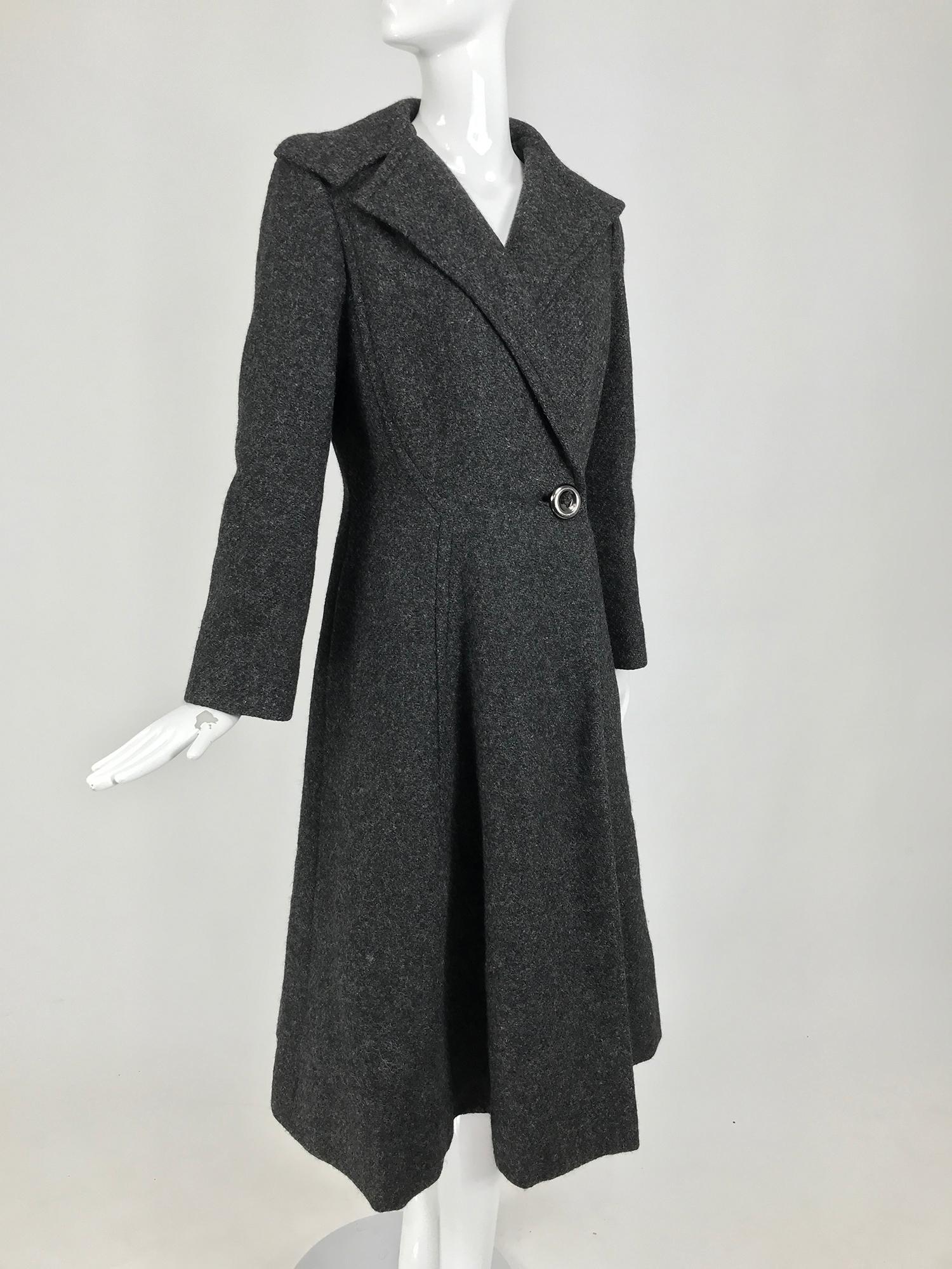Pauline Trigere grey flecked wool princess coat from the 1950s. Dark charcoal grey flecked wool coat with wide shaped lapels closes at the waist with a single silver metal button. The coat has a fitted waist, the skirt flares to the hem. The coat