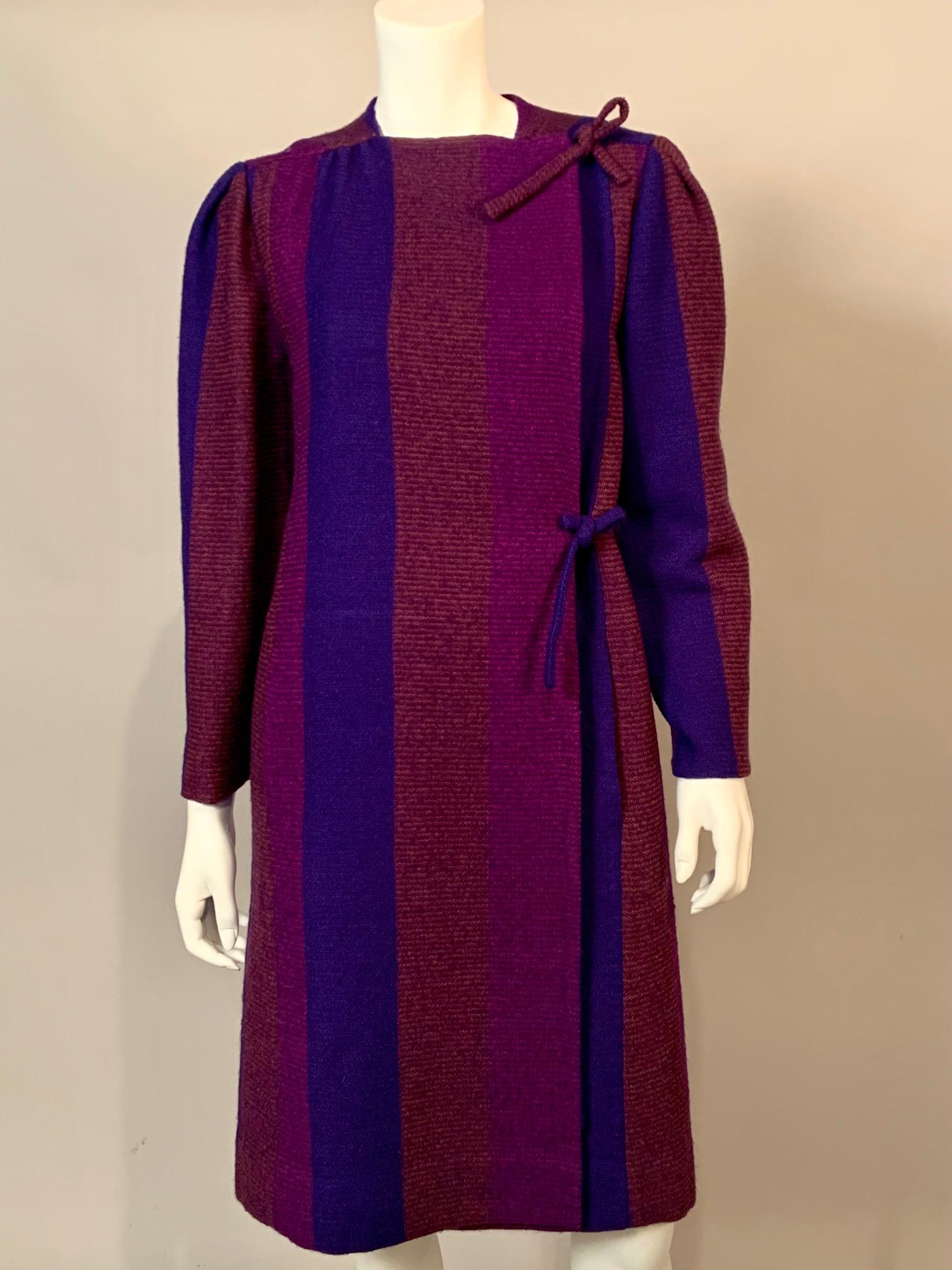 Pauline Trigere designed this outfit using a fantastic vertical striped wool in purple, electric blue and rust. The coat has one snap at the neckline and two wool ties on the left side. The wrap around skirt has hooks and eyes at the waist band and