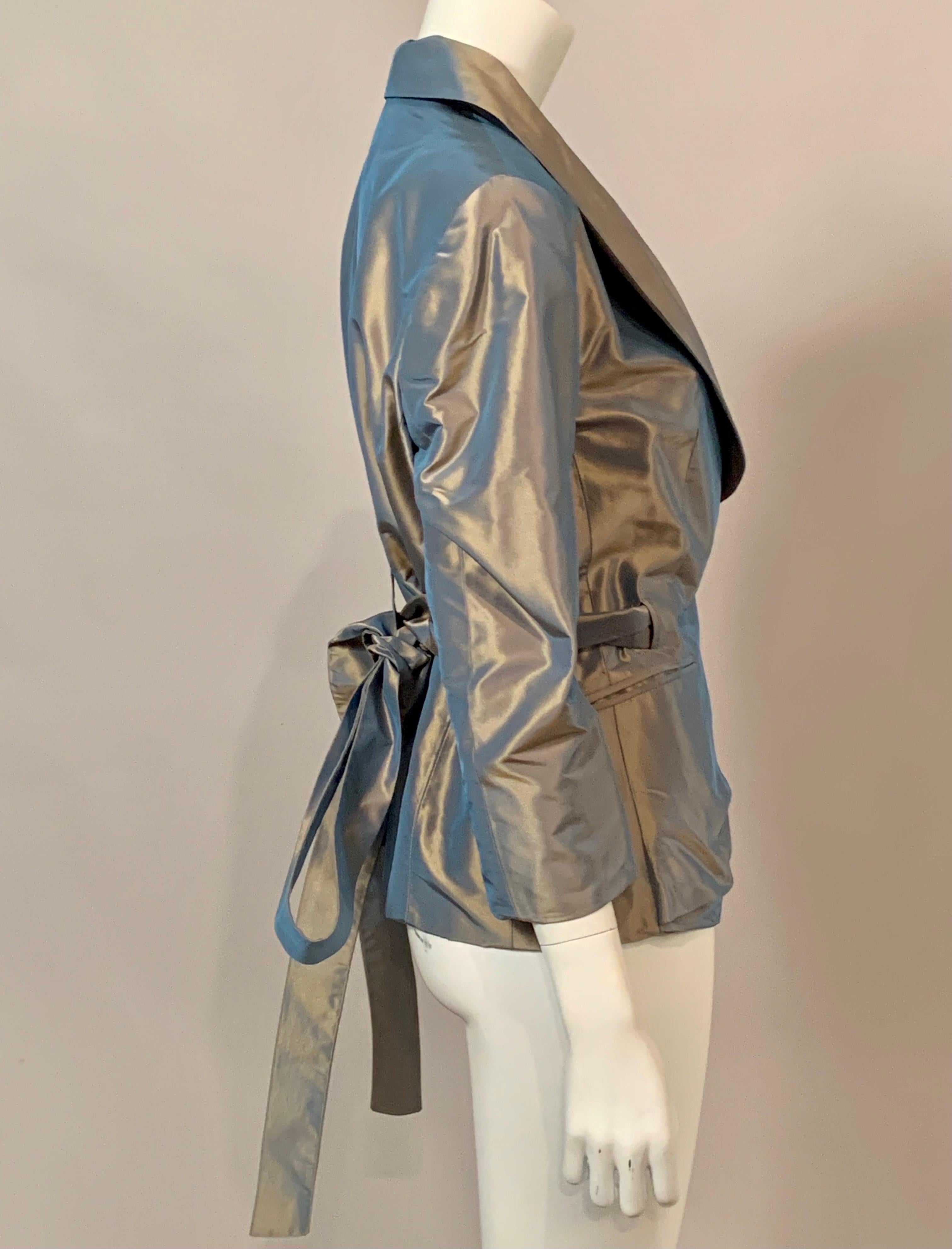 Cette superbe veste en soie grise irisée présente de nombreuses touches de design intéressantes, notamment les revers incurvés, une ceinture à nouer qui se transforme en un gros nœud dans le dos, une poche avec un rabat intéressant et une poche sans