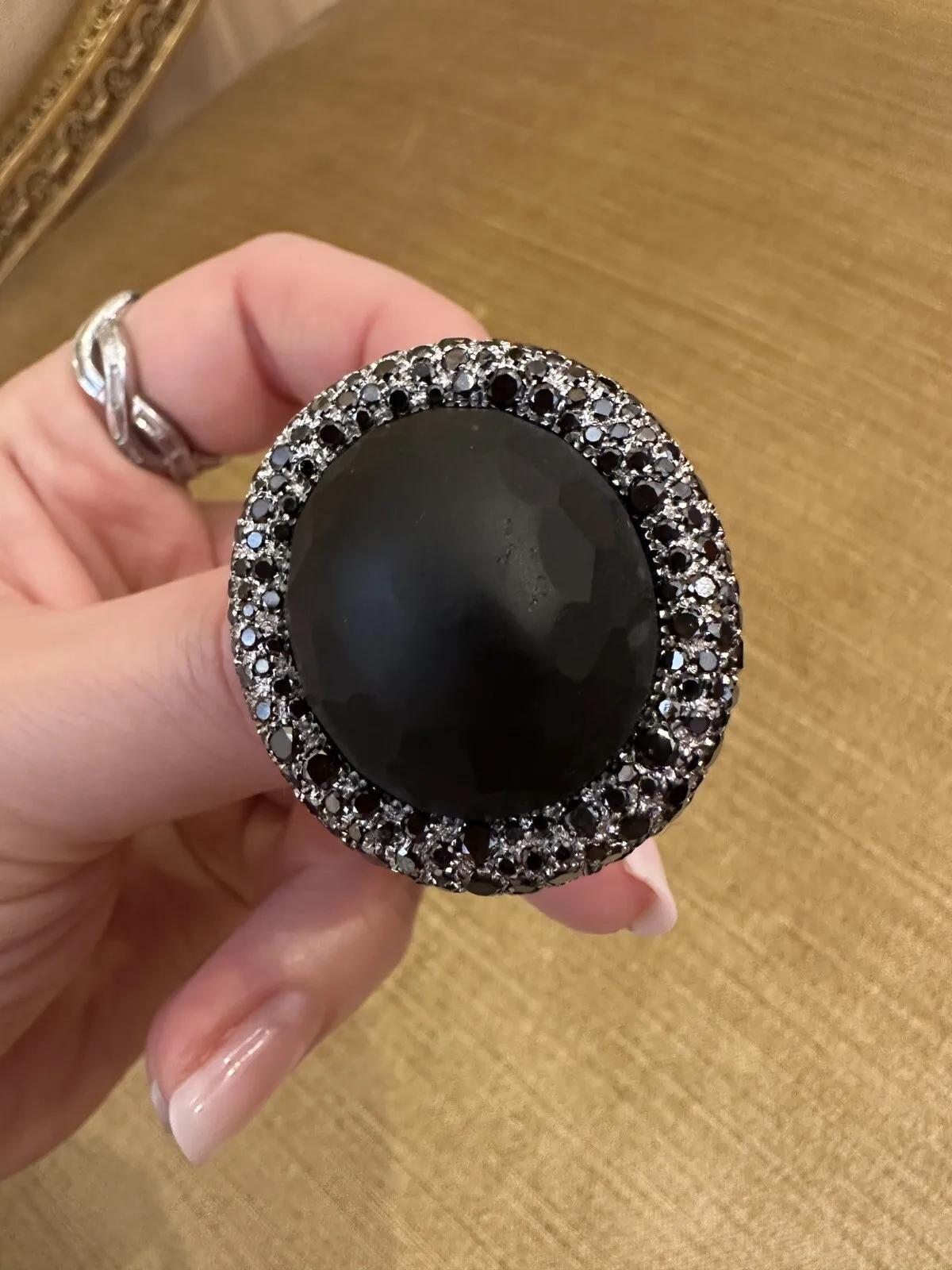 Bague en or blanc 18k avec diamant noir et obsidienne

La bague en obsidienne et diamant noir présente une obsidienne noire mate ovale entourée de diamants noirs ronds pavés en or blanc 18 carats.

L'obsidienne pèse 48,80 carats, a une finition mate