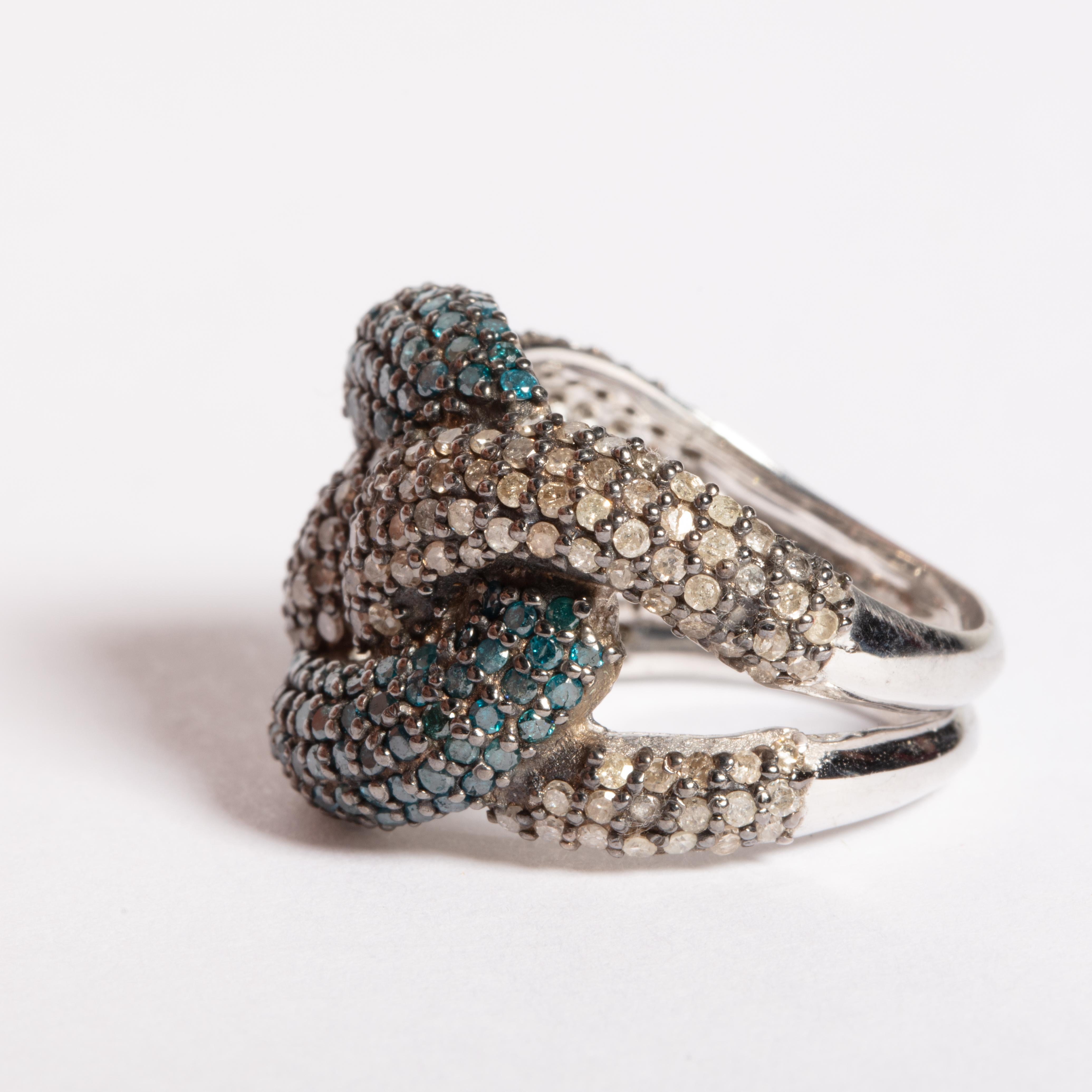 An unusual knot design of pave`-set diamonds and blue diamonds set in sterling silver.  Carat weight of diamonds is 2,25 and sapphires are 1.78 carats.  Ring size is 7.

The fine jewelry collection is sourced, designed or created by Deborah Lockhart