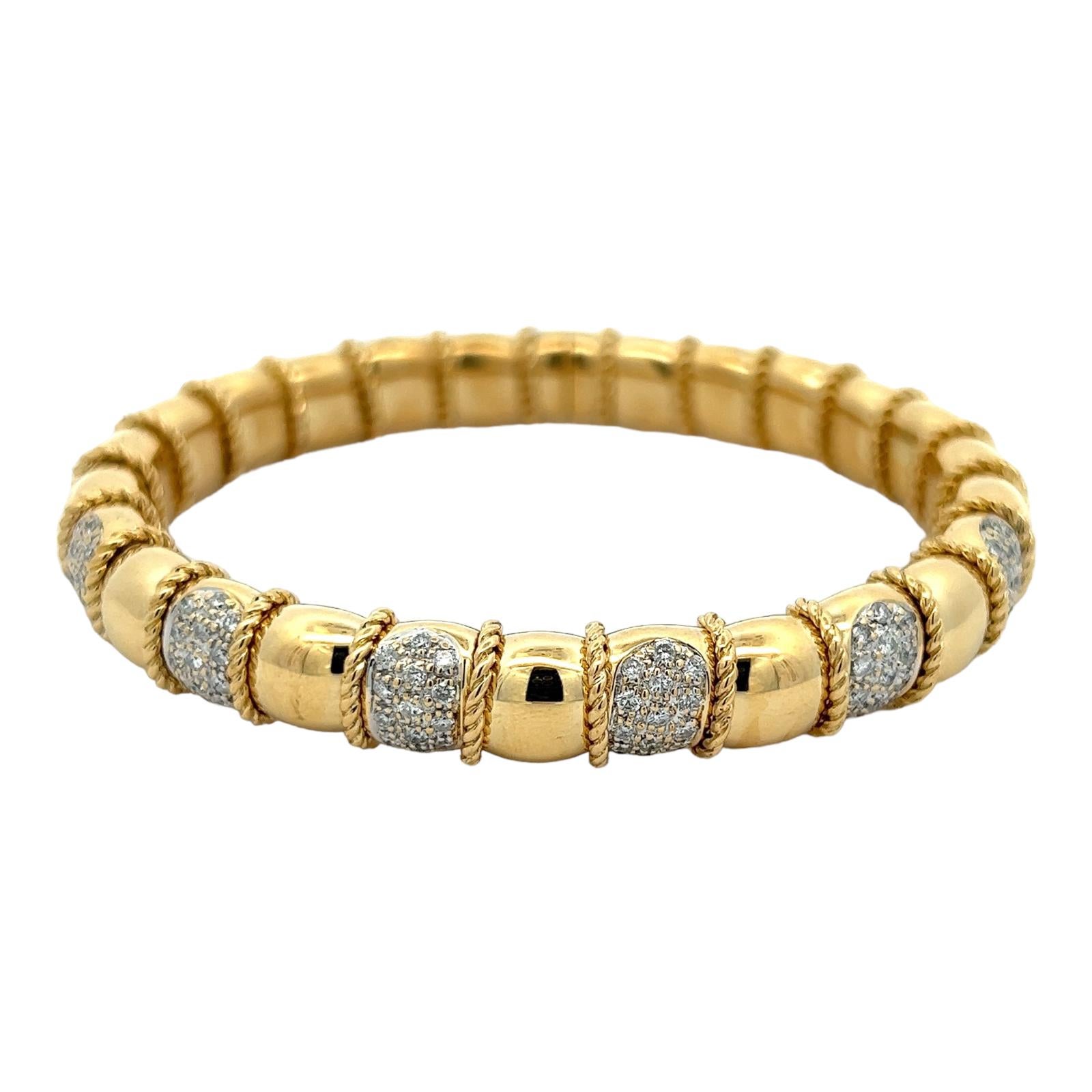 Pavé diamond flexible cuff bracelet crafted in 18 karat yellow gold. The bangle features 78 round brilliant cut diamonds weighing approximately 1.50 CTW and graded H-I color and SI clarity. The cuff is flexible for easy wear and measures 2.25 inches
