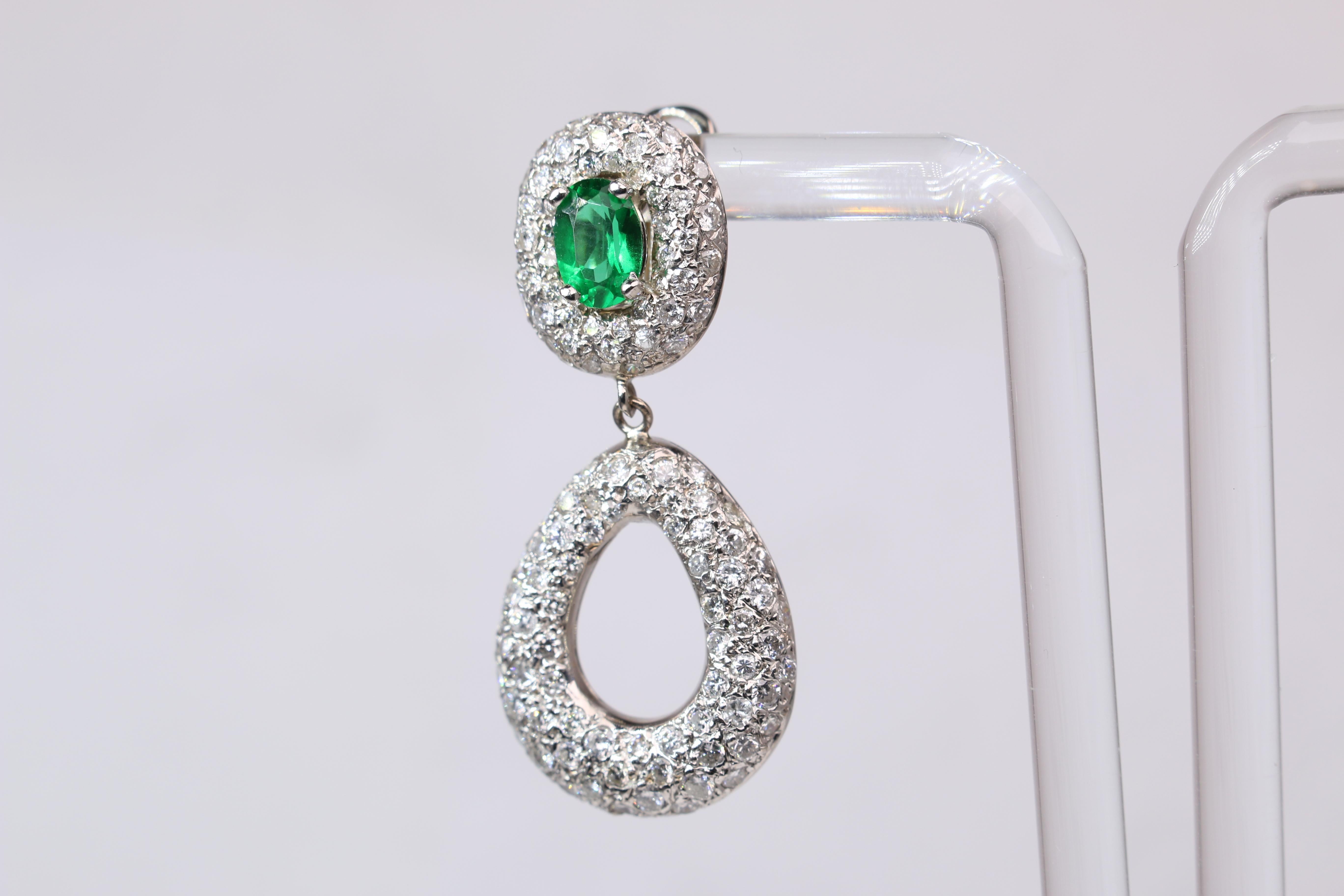 These stunning oval emerald and pave diamond earrings are set in 18k White Gold. The earrings weigh 13.2g in total and feature two oval cut emeralds measuring 7mm X 5mm. The earrings are 1.5 inches in length and 6/8 of an inch wide. A truly stunning