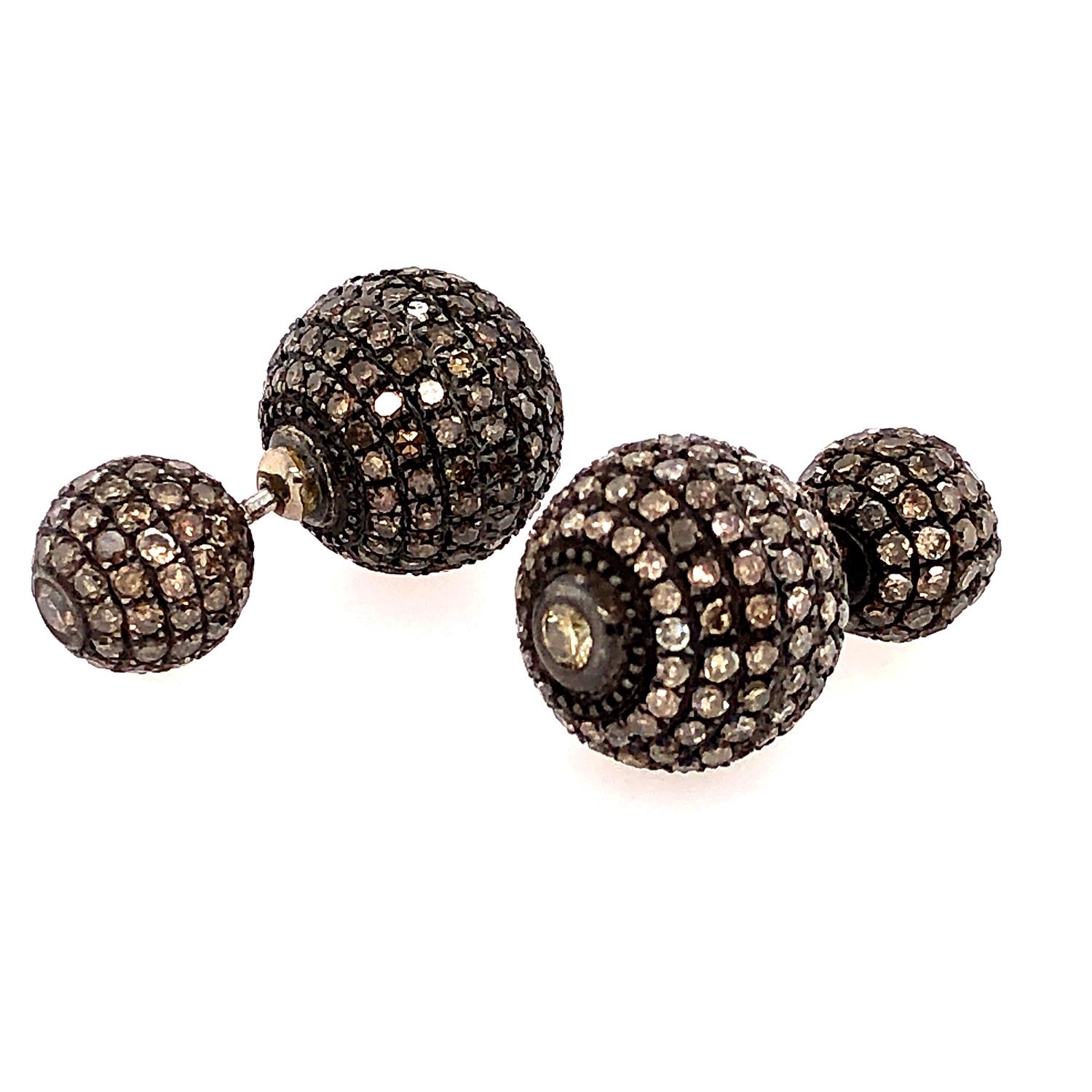 The earrings feature a round ball shape, encrusted with sparkling diamonds in a pave setting. These earrings a tunnel design, which allows them to be worn through the earlobe for a stylish and modern look. These earrings are perfect for dressing up