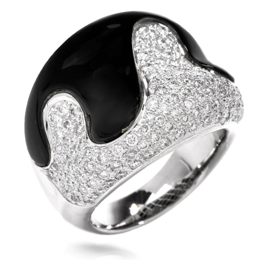 This stylish ring of bold and opulent design is crafted in 18 karat white gold and weighs approximately 15.5 grams. Designed as a gracefully concave, wide plaque, with asymmetric juxtaposition of pave diamonds and artfully caliber-carved black onyx,