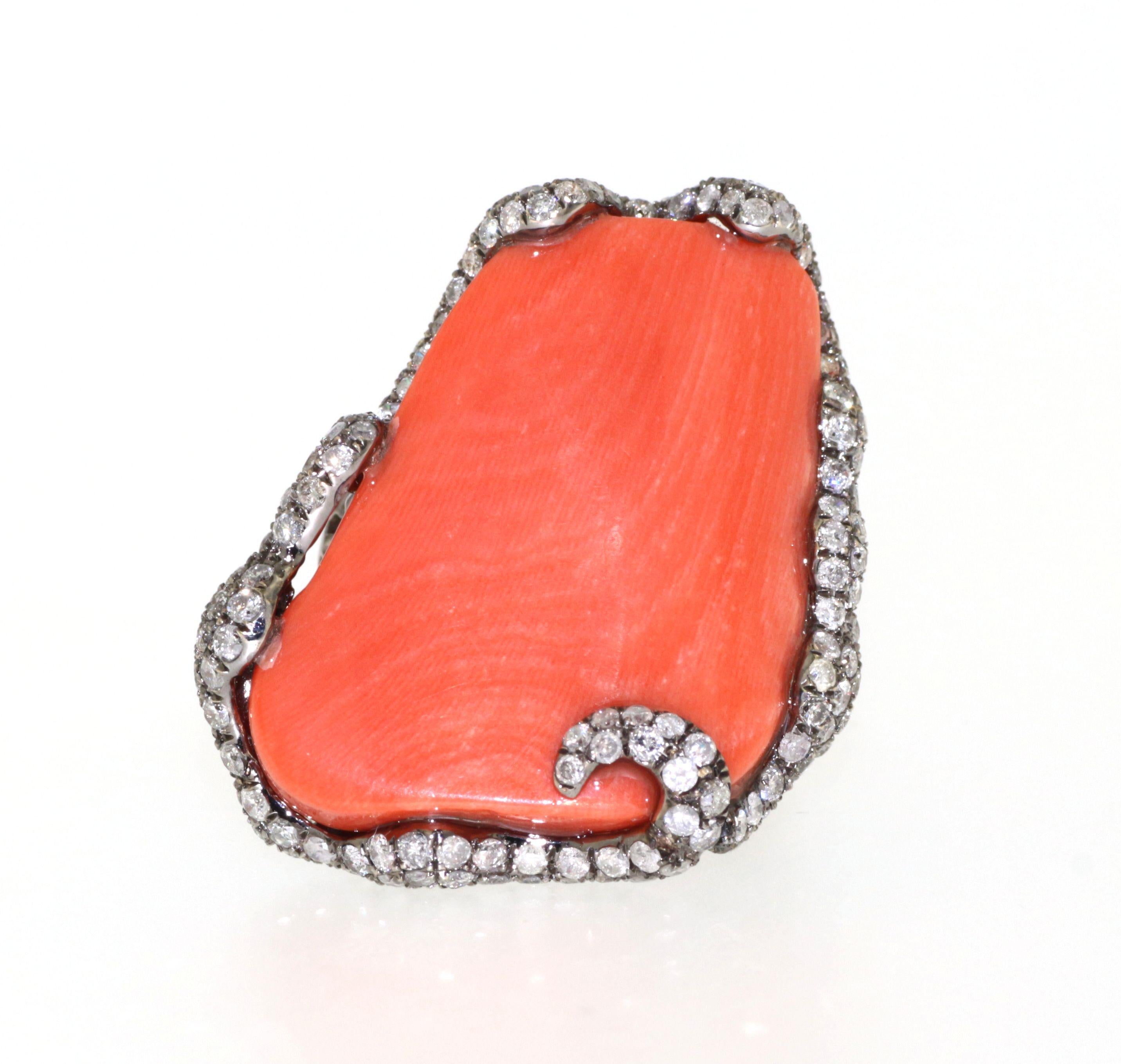 This magnificent ring features a large, smooth coral centerpiece weighing 6.98 grams, enveloped in a luxurious embrace of sparkling white diamonds totaling 0.85 carats and natts diamonds of 1.72 carats. The coral's warm, rich hue is beautifully