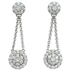 Boucles d'oreilles pendantes en or blanc 18 carats avec pavé de diamants et halo.