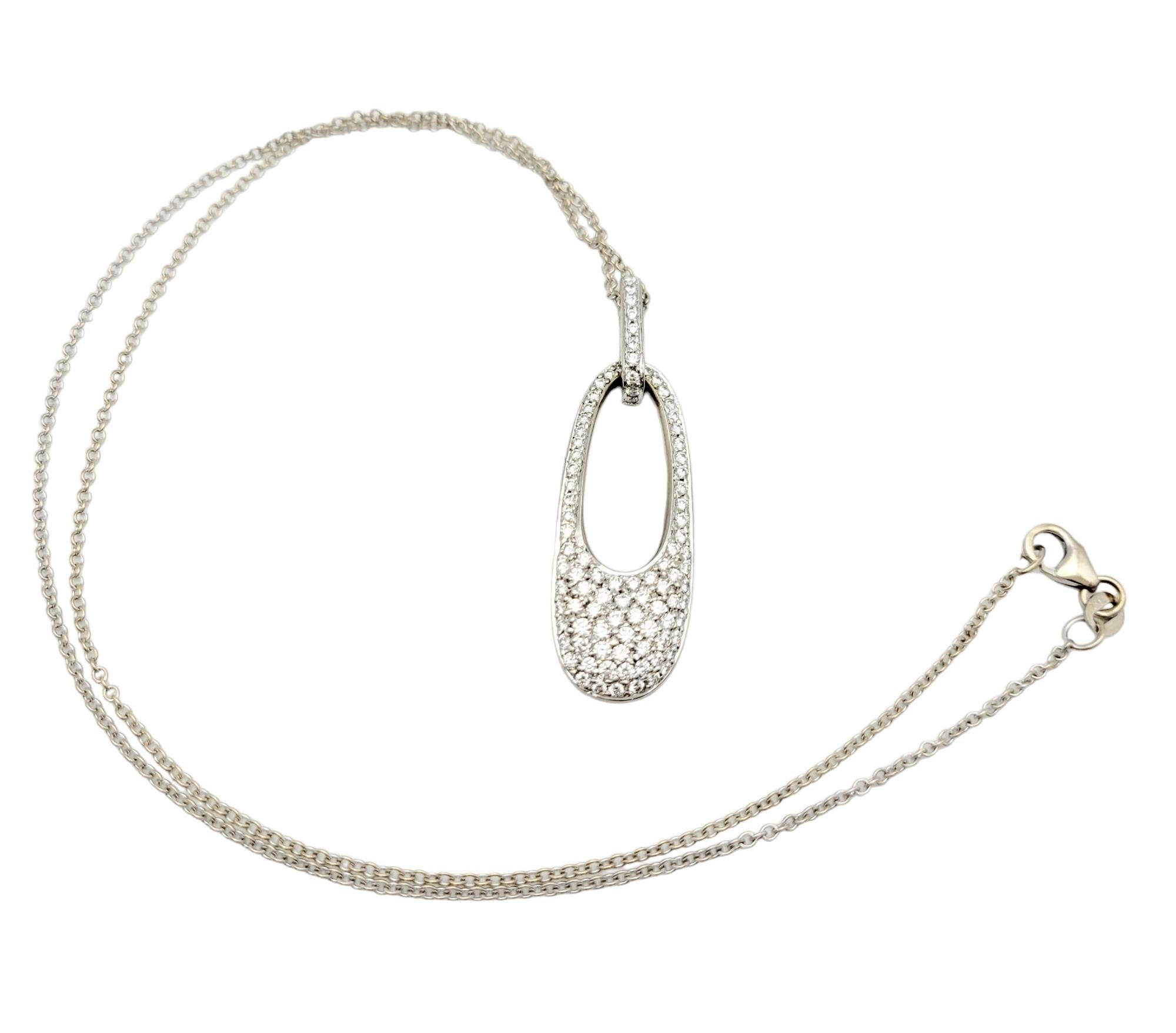 This exquisite drop pendant necklace is a radiant expression of sophistication and glamour. Crafted from lustrous 14 karat white gold, the pendant assumes the form of an elongated open oval, creating a visually captivating silhouette. The entire