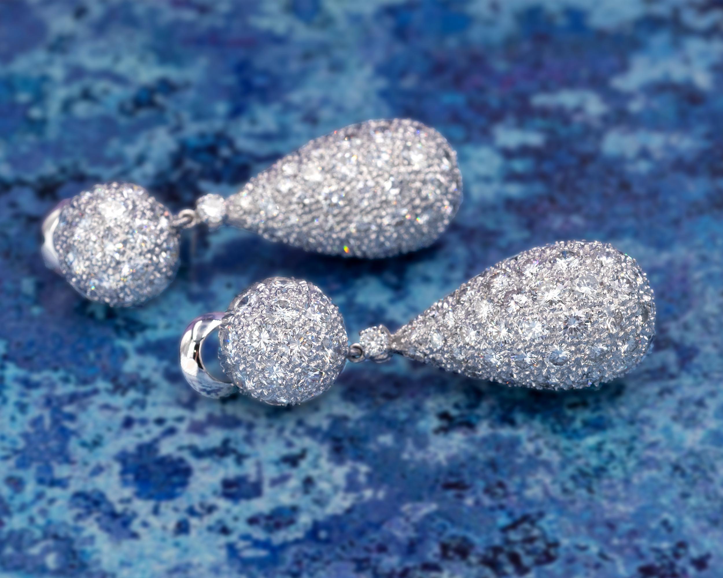 Important platinum pavé-set dangle earrings consisting each of half a sphere that bears the clip-on mechanism and a pear-shaped drop, both fully set with diamonds which are unusually big for a pave setting. That gives these drop earrings a sparkling