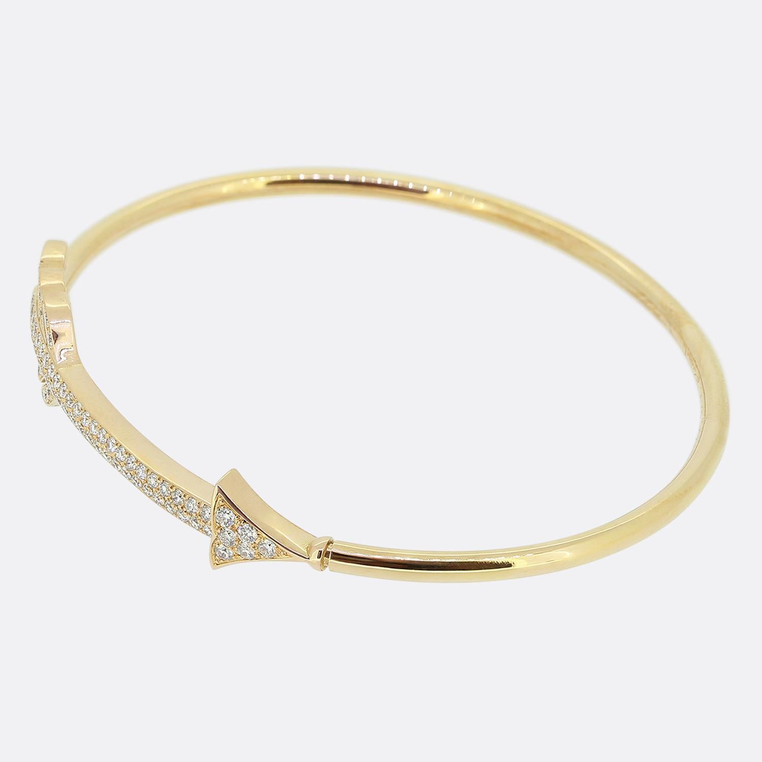 Here we have a beautiful diamond bangle crafted from 18ct gold. A slim warm yellow band play host to a rose gold arrow design at the front of the face which has been entirely pavé set with a vast array of round brilliant cut diamonds. The piece is