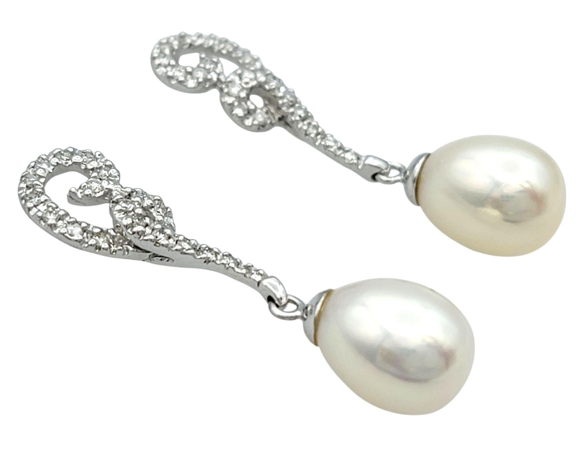 Eleganza e luminosità, questi orecchini pendenti con perle coltivate e diamanti sono un cenno romantico all'eleganza senza tempo. Realizzato in oro bianco da 14 carati, il design presenta due perle d'acqua dolce a forma di goccia in una tonalità