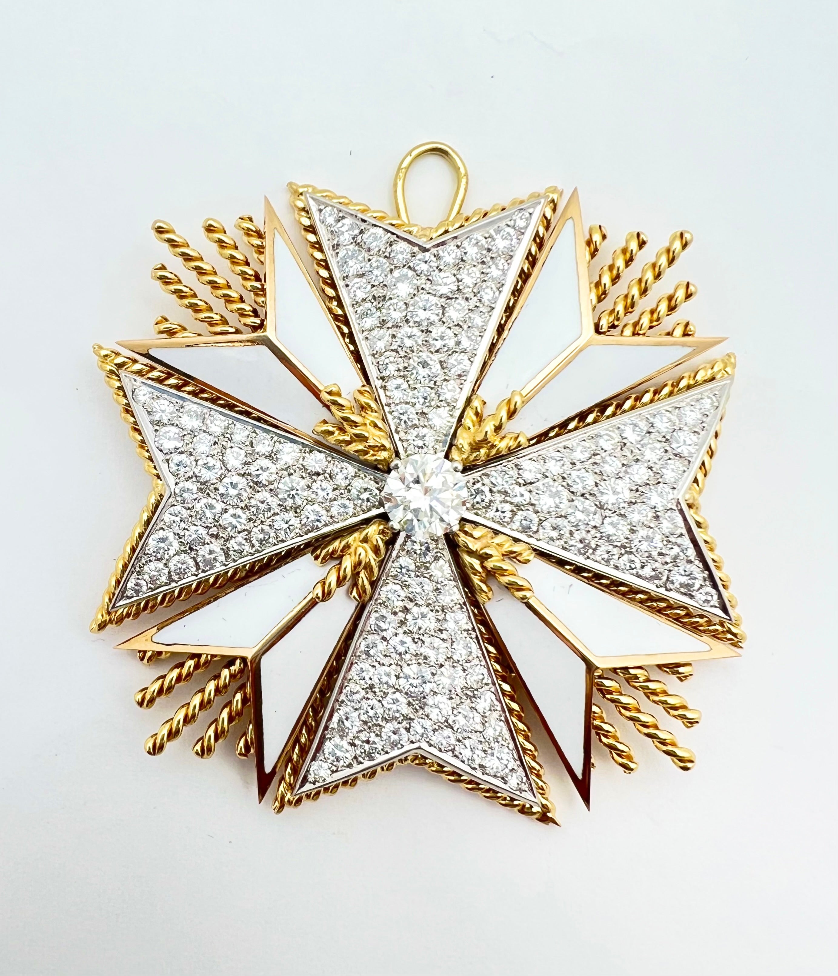 Maltese cross clip brooch in 18k yellow gold, white enamel and natural diamonds.  Worn as a pendant or brooch, this beautifully handcrafted piece centers a round brilliant-cut diamond weighing approximately 1.03 carats, and the four corners of the