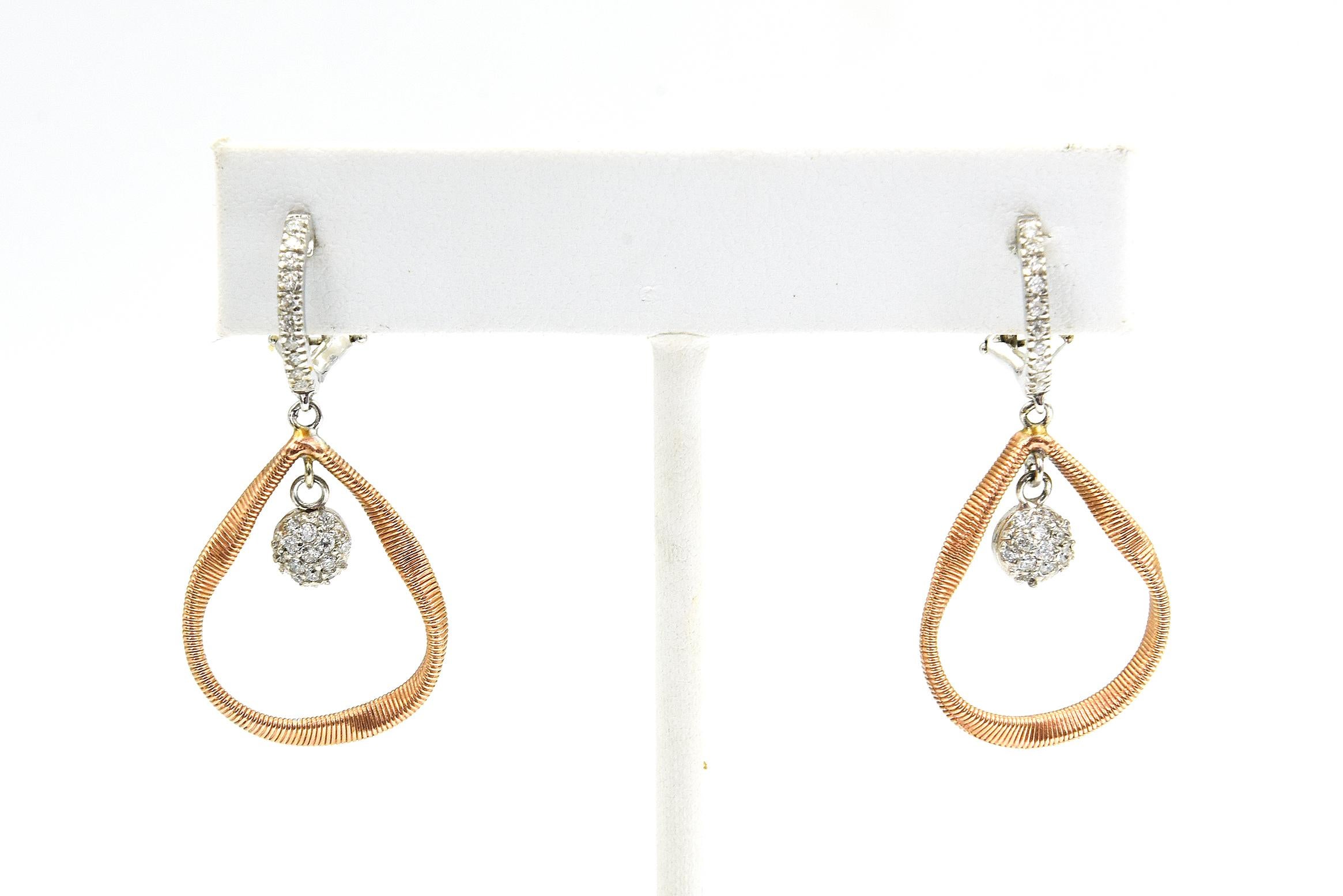 Orecchini di diamanti in oro bianco e rosa 14k con un cerchio di diamanti in oro bianco sull'orecchio e un diamante rotondo in pavé che penzola all'interno di una montatura a forma di pera in oro rosa ritorta. Per indossare questi orecchini è