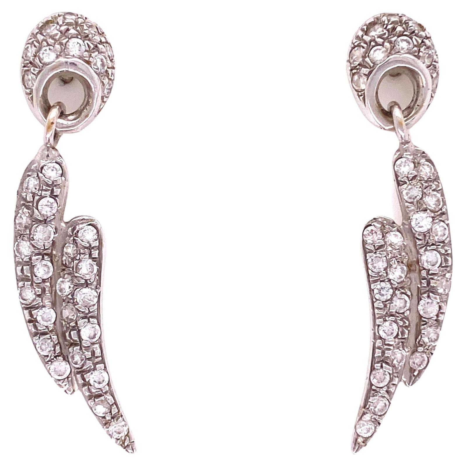Boucles d'oreilles pendantes en or avec motifs d'ailes en diamant pavé.