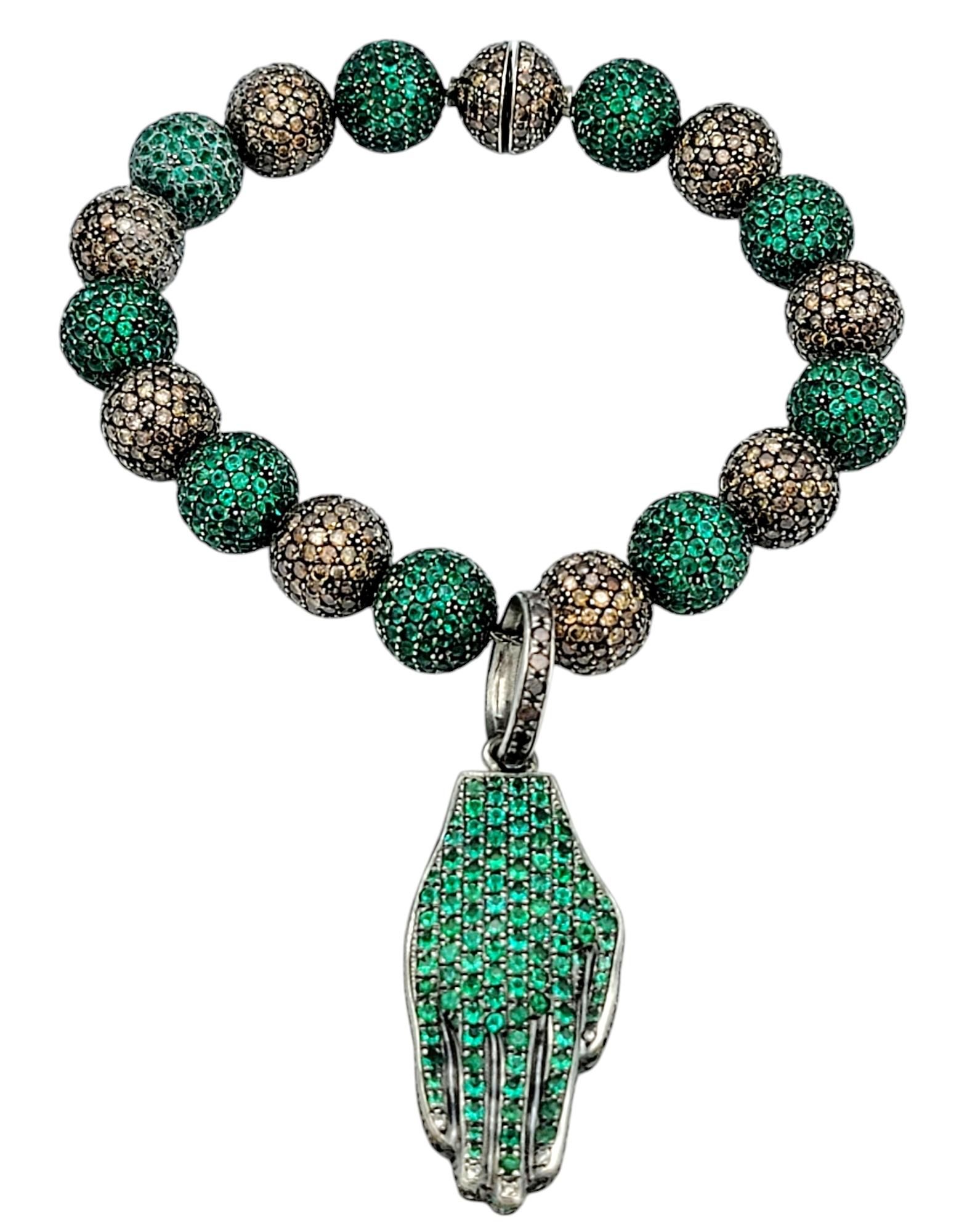 Questo straordinario bracciale charme con smeraldi e diamanti è un'affascinante dimostrazione di intricata maestria e design opulento. Il bracciale presenta un filo di perline alternate di smeraldi e diamanti di taglio rotondo, che creano una