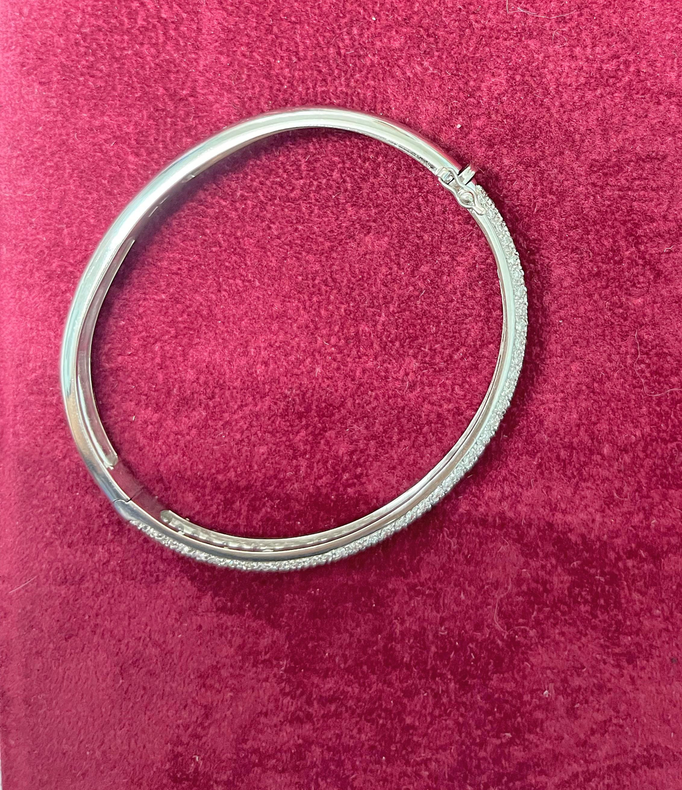 Un look classico e di facile eleganza, questo bracciale bangle con diamanti emana raffinatezza. 
Questo splendido e brillante bracciale è realizzato in oro bianco 18 carati e presenta piccoli diamanti bianchi a taglio rotondo incastonati con un peso