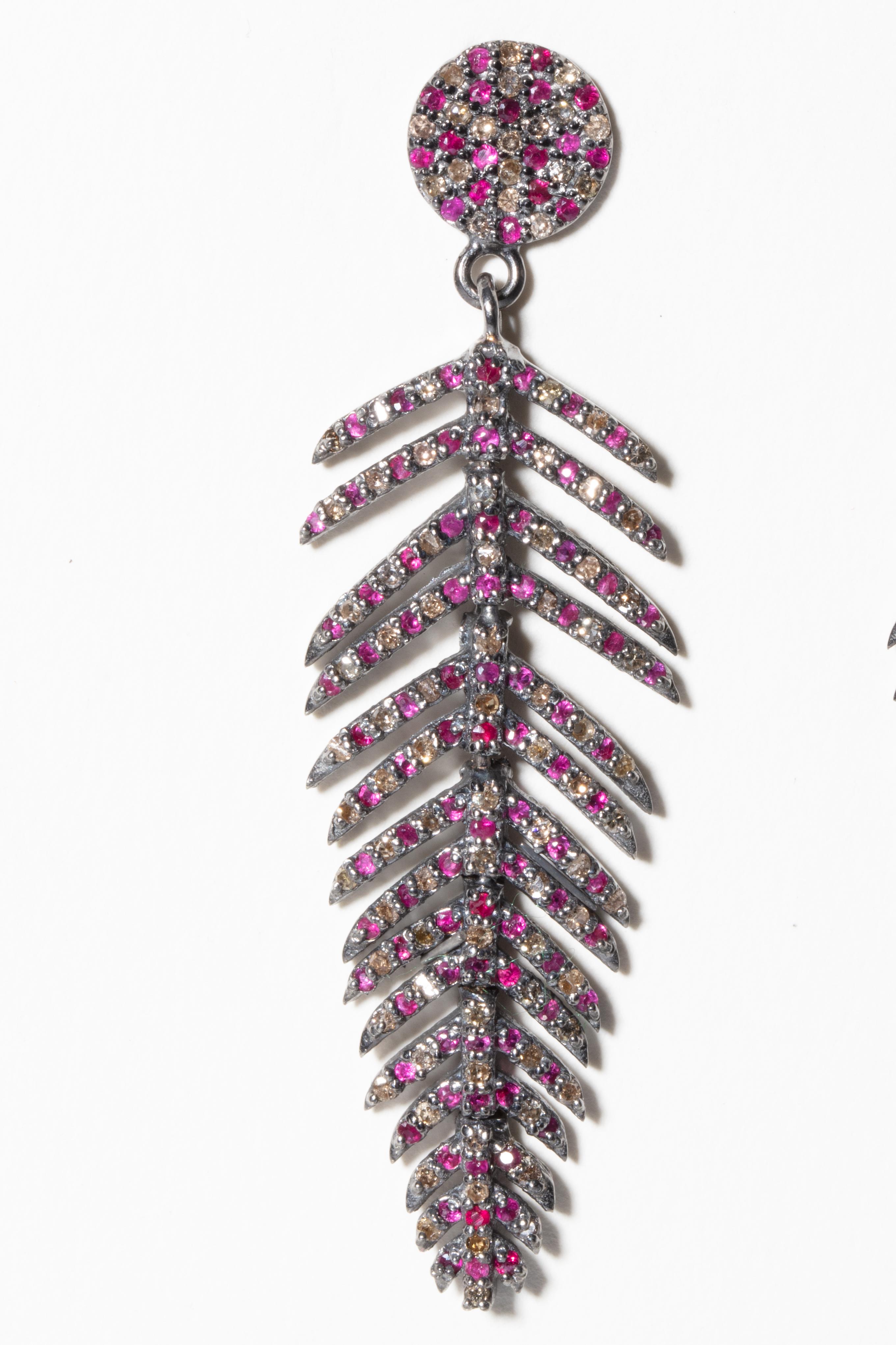 A pair of brilliant-cut, pave`-set diamond and Burmese ruby feather earrings.  Set in an oxidized sterling silver with 18K gold post for pierced ears.  Weight of diamonds is 1.10 carats, rubies are 1.66 carats.  An articulated spine offers movement