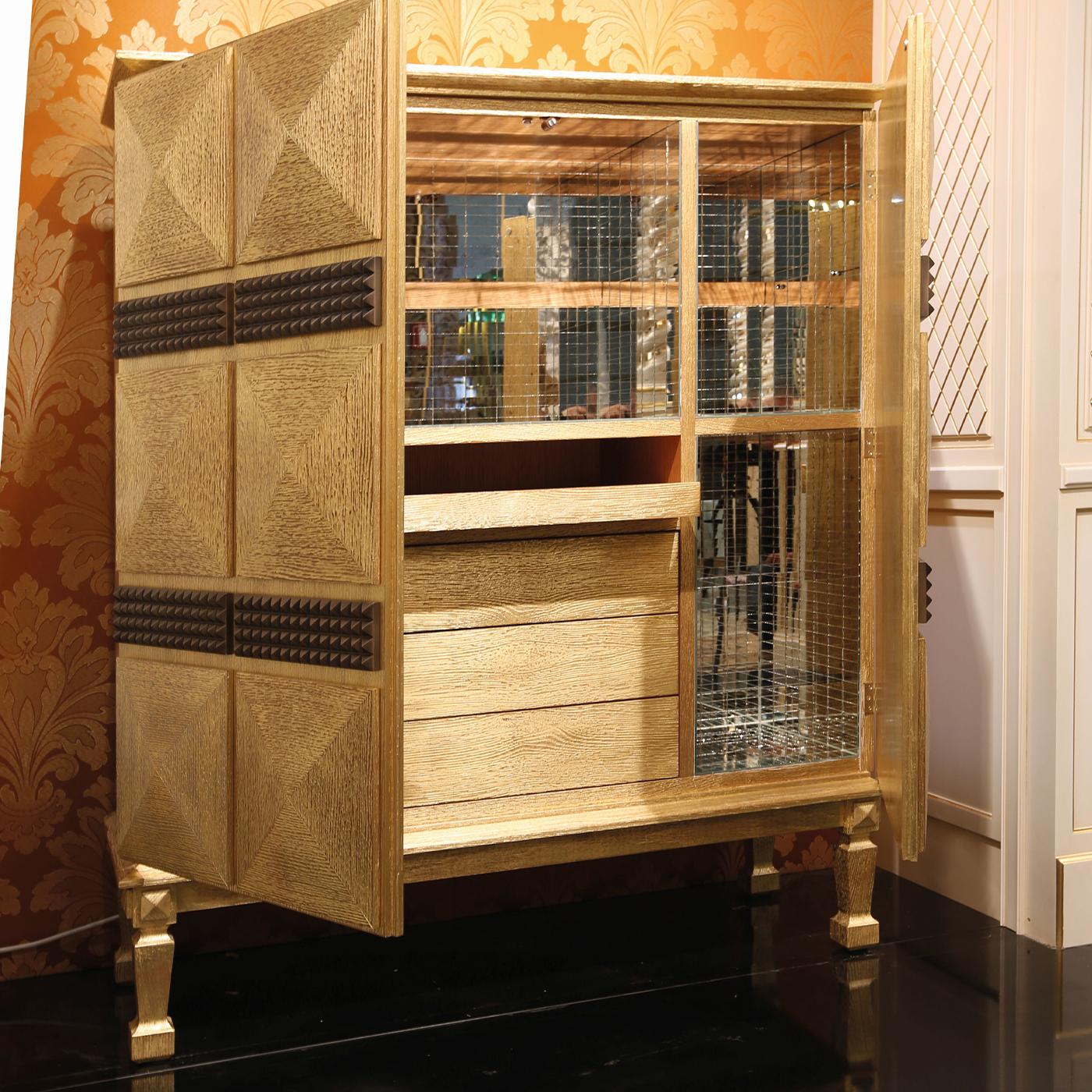 Stately and sultry, this bar cabinet will effortlessly fit in a sophisticated, Art Deco-inspired living room. The imposing structure standing on four sculpted feet is fashioned of pickled oak and extensively covered with prized gold leaf for a luxe
