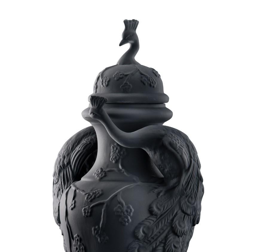 This striking ceramic vase with lid, entirely finished with a black matte polish, is magnificently decorated with two peacocks, whose feathers rest on the sides of the base, along with delicate flowered branches.