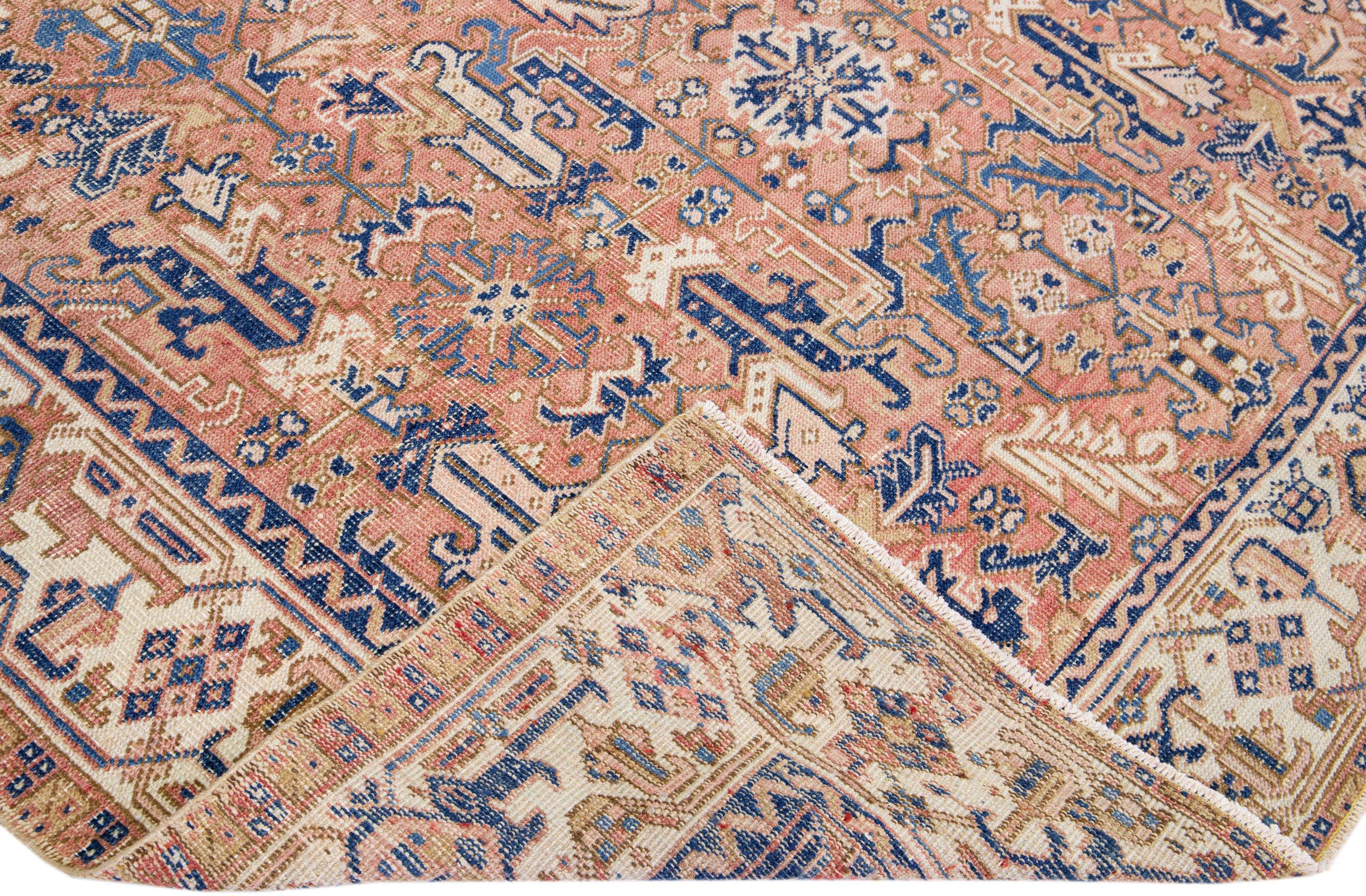 Schöne antike Heriz handgeknüpfte Wolle Teppich mit einem Pfirsich Farbfeld. Dieser Perserteppich hat einen beigen Rahmen mit blauen Akzenten in einem herrlichen geometrischen Blumenmuster.

Dieser Teppich misst: 7'8