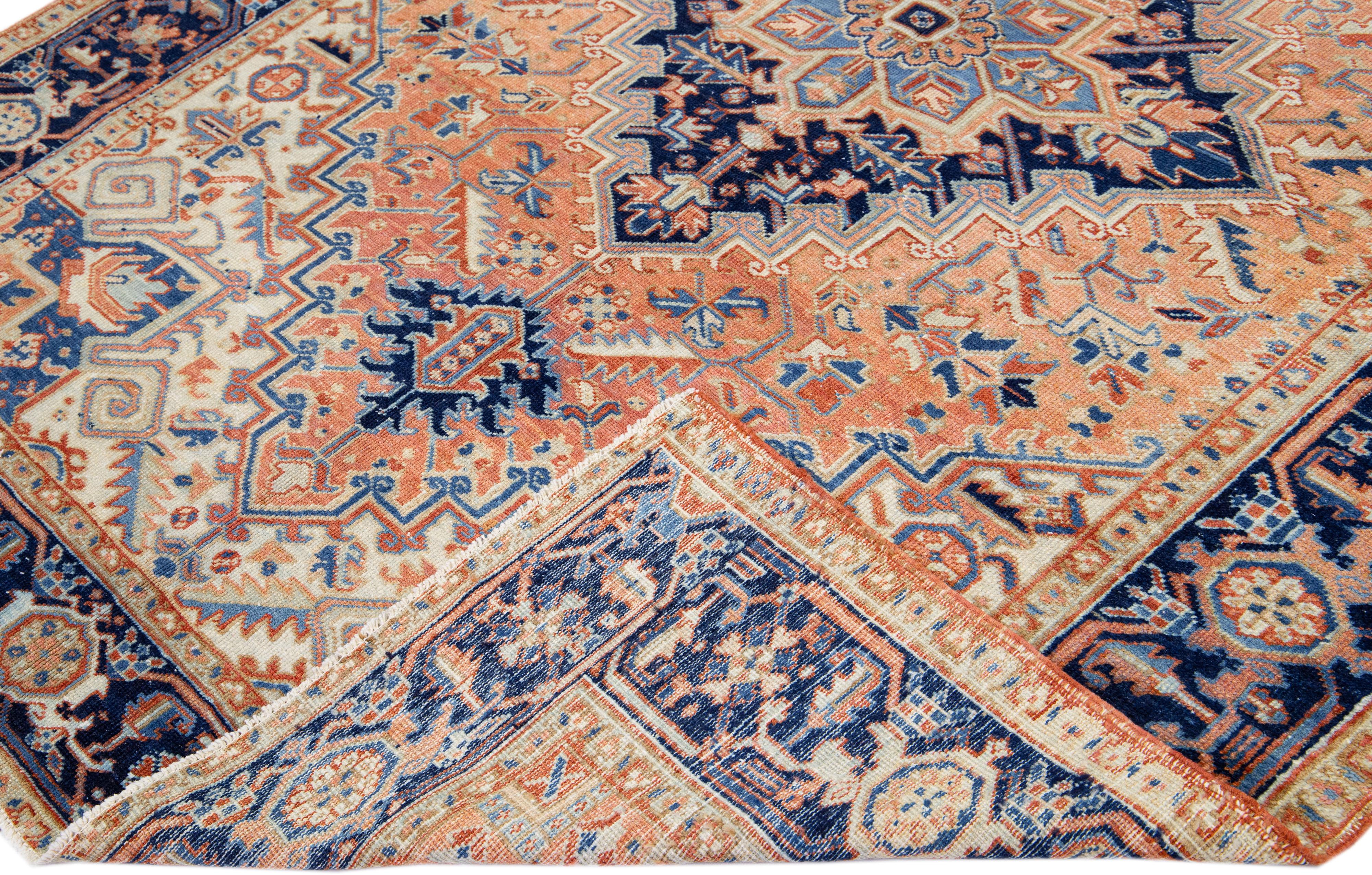 Beautiful antique Heriz hand-knotted wool rug with a peach color field. This Persian rug has a blue frame with beige accents in a gorgeous all-over geometric floral medallion design.

This rug measures: 6'6