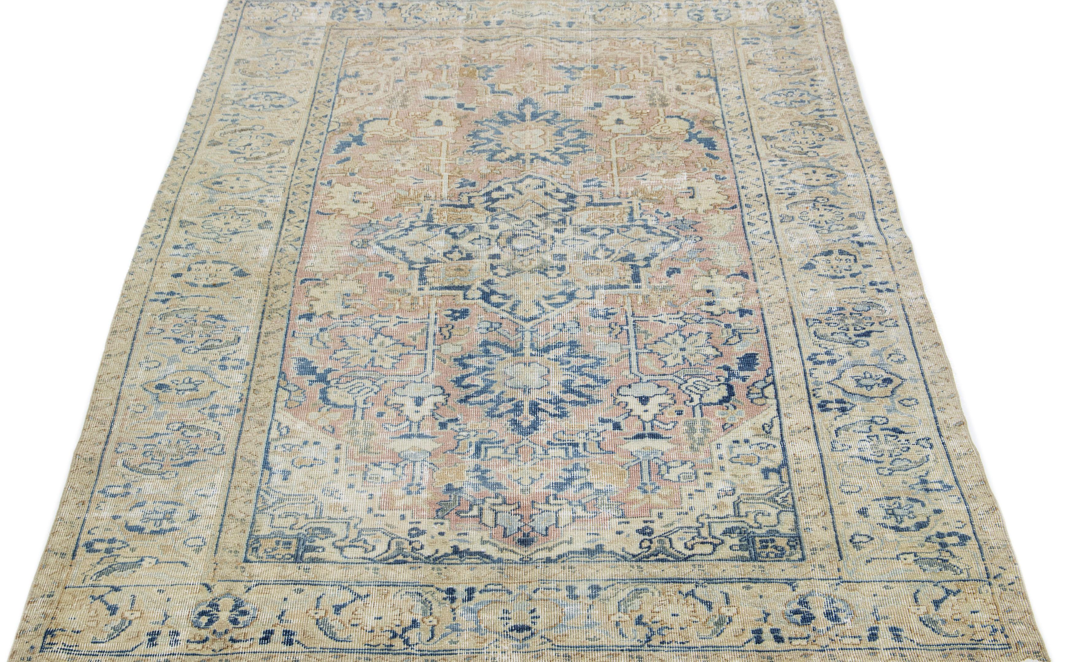 The Persian rug displays an exquisite all-encompassing design, featuring a floral medallion and geometric motif in shades of blue and beige, set against a peach-toned field.

This rug measures 5.9
