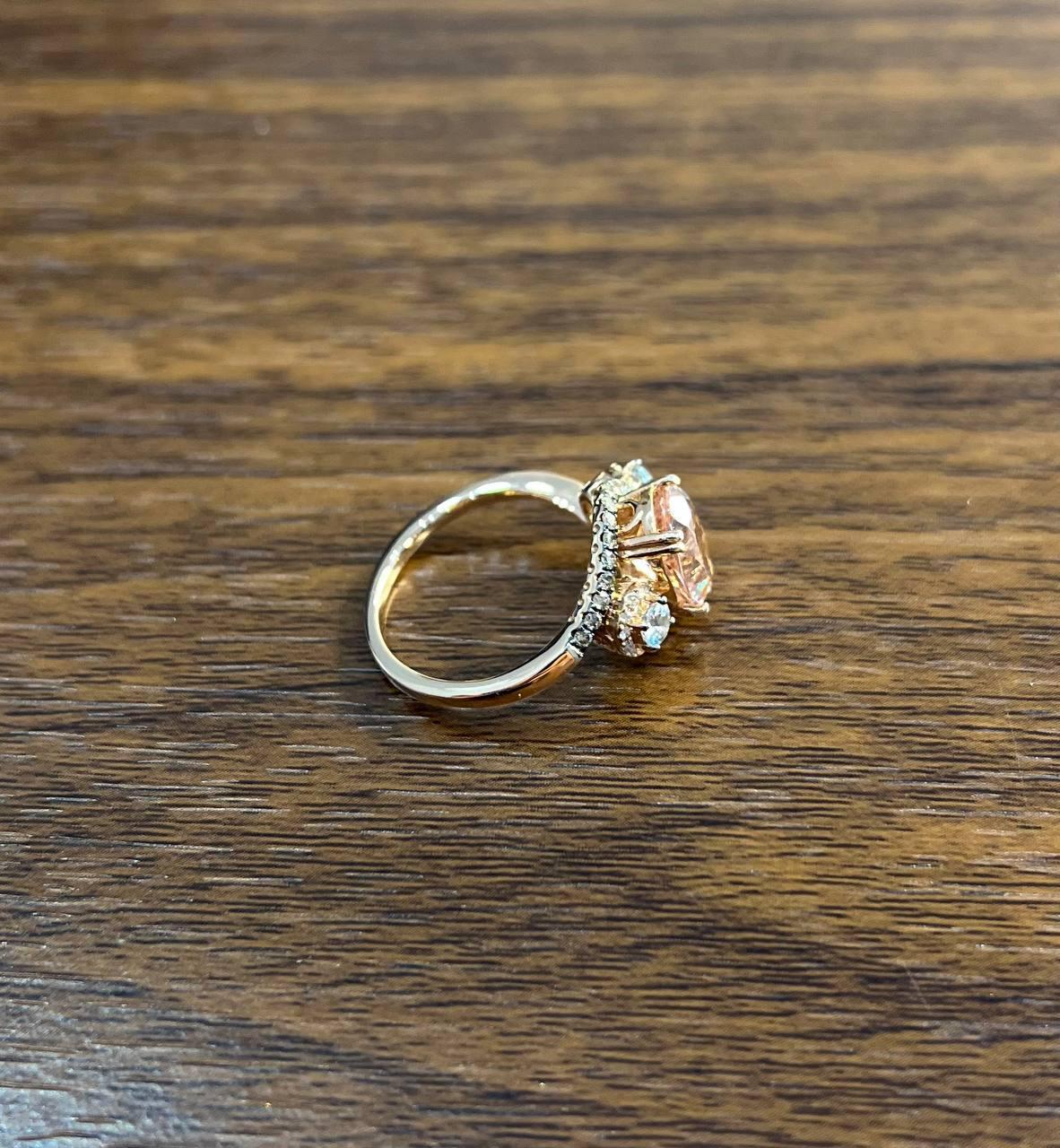 Radiant and Elegant. Set with a Central Peach Morganite. Accented by Sparkling White Champagne Diamonds and Blue Topaz. 14K Rose Gold.
