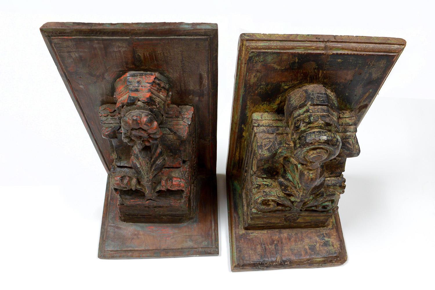 Two ornately hand carved wooden brackets. The one with the red paint remnants features a peacock with a floral surround (there is some damage to the main flower) Its dimensions are 29cm wide x 56cm high x 23.5cm deep. The one with the green paint