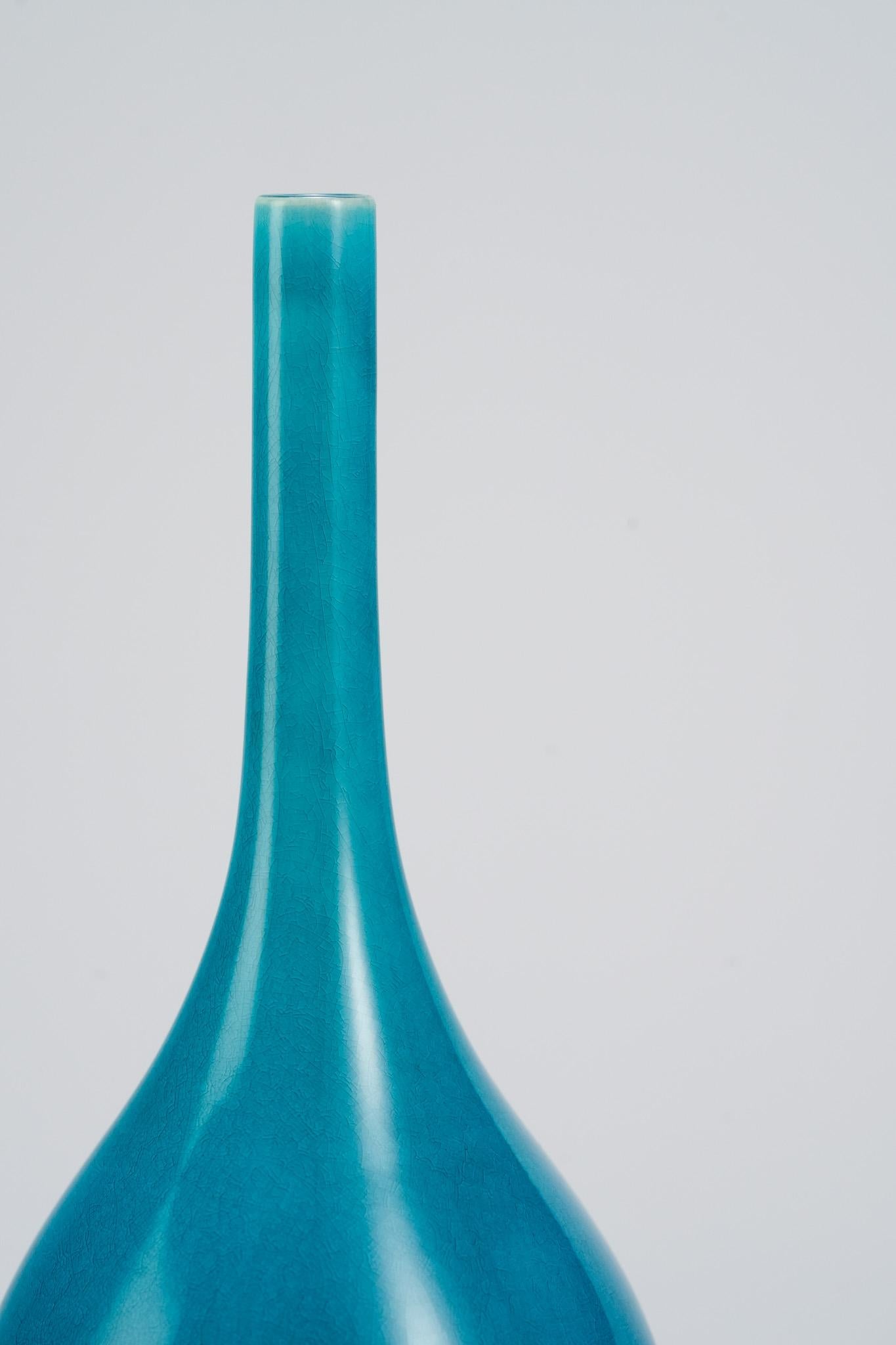 Ce vase à long col bleu paon de Shi Jie Weng se distingue par ses couleurs éclatantes et ses proportions élégantes. La glaçure se transforme naturellement de haut en bas en un doux dégradé, créant un effet rappelant la lumière se répandant sur un