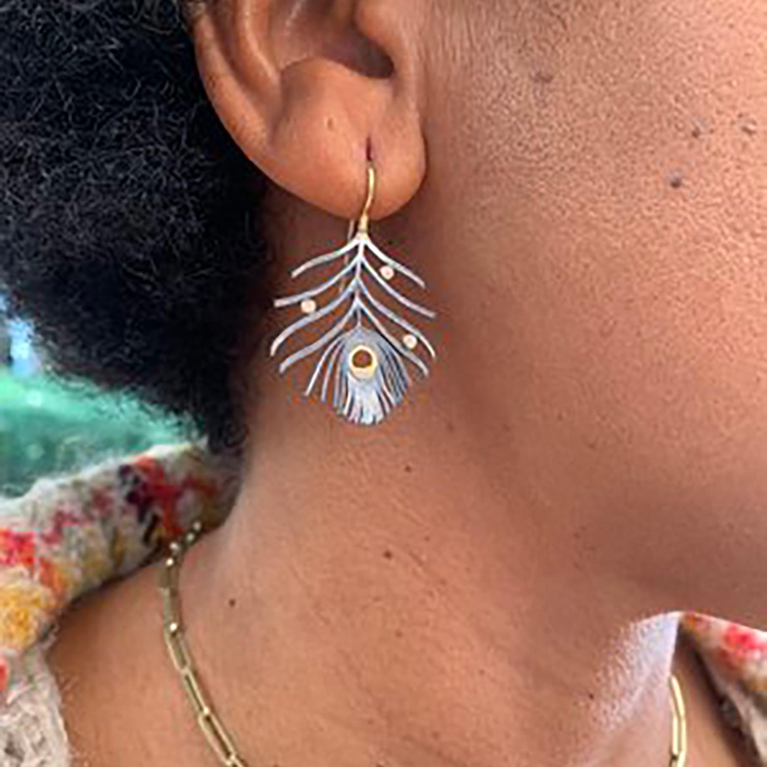 These gorgeous earrings evoke the beauty and elegance of peacock feathers.  The delicate oxidized sterling silver feathers are sprinkled with natural rose cut diamonds that are wrapped in lustrous 18k yellow gold. You will feel graceful and stylish