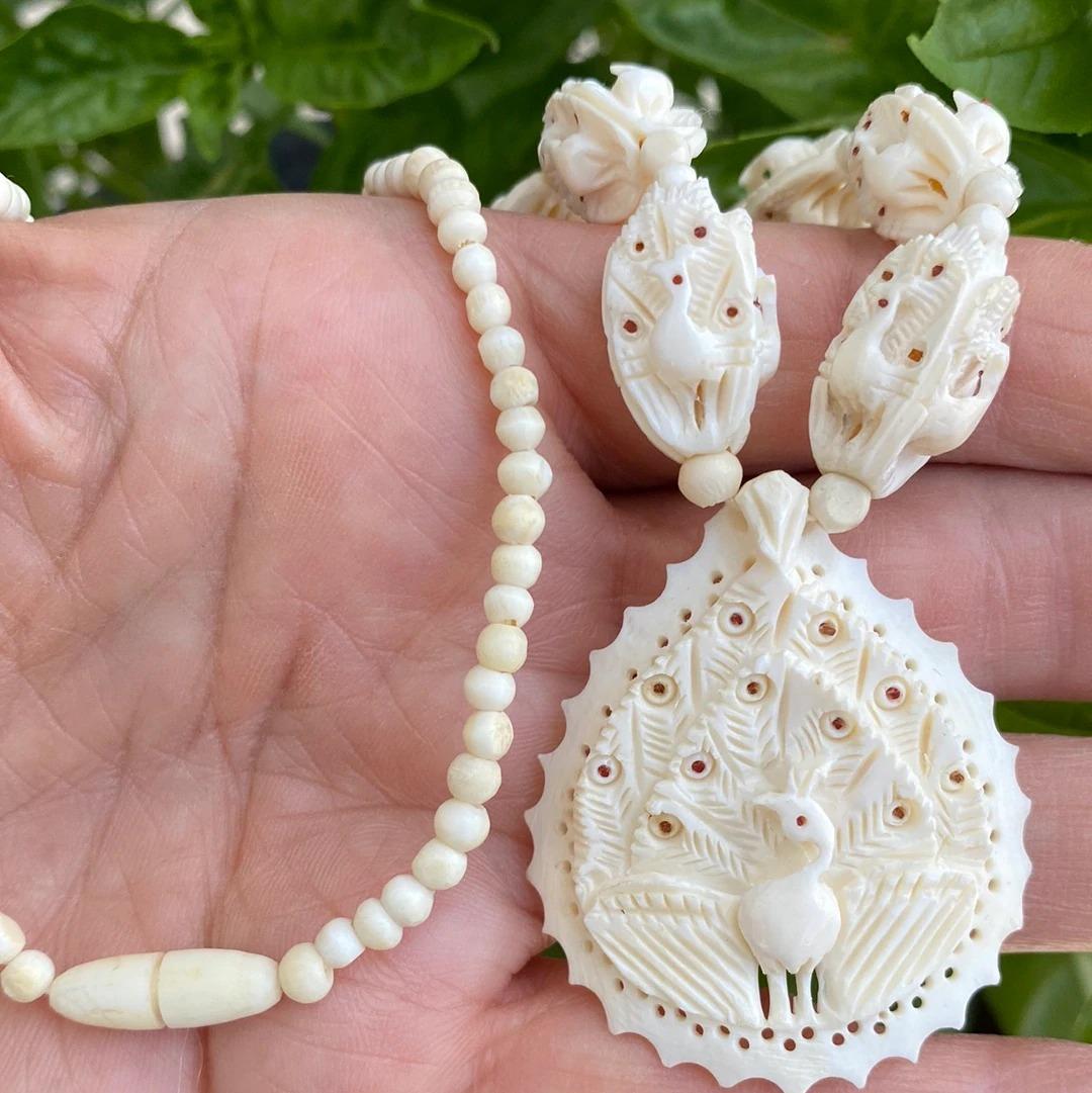  10 carved peacock beads are extended on a necklace measuring 16 inches. 
The ivory colored beads measure 12 mm x 18 1/2 mm and increase up to 21 mm in length nearest a dangly Pendant

The pendant is a beautiful peacock-shaped pendant measuring 42
