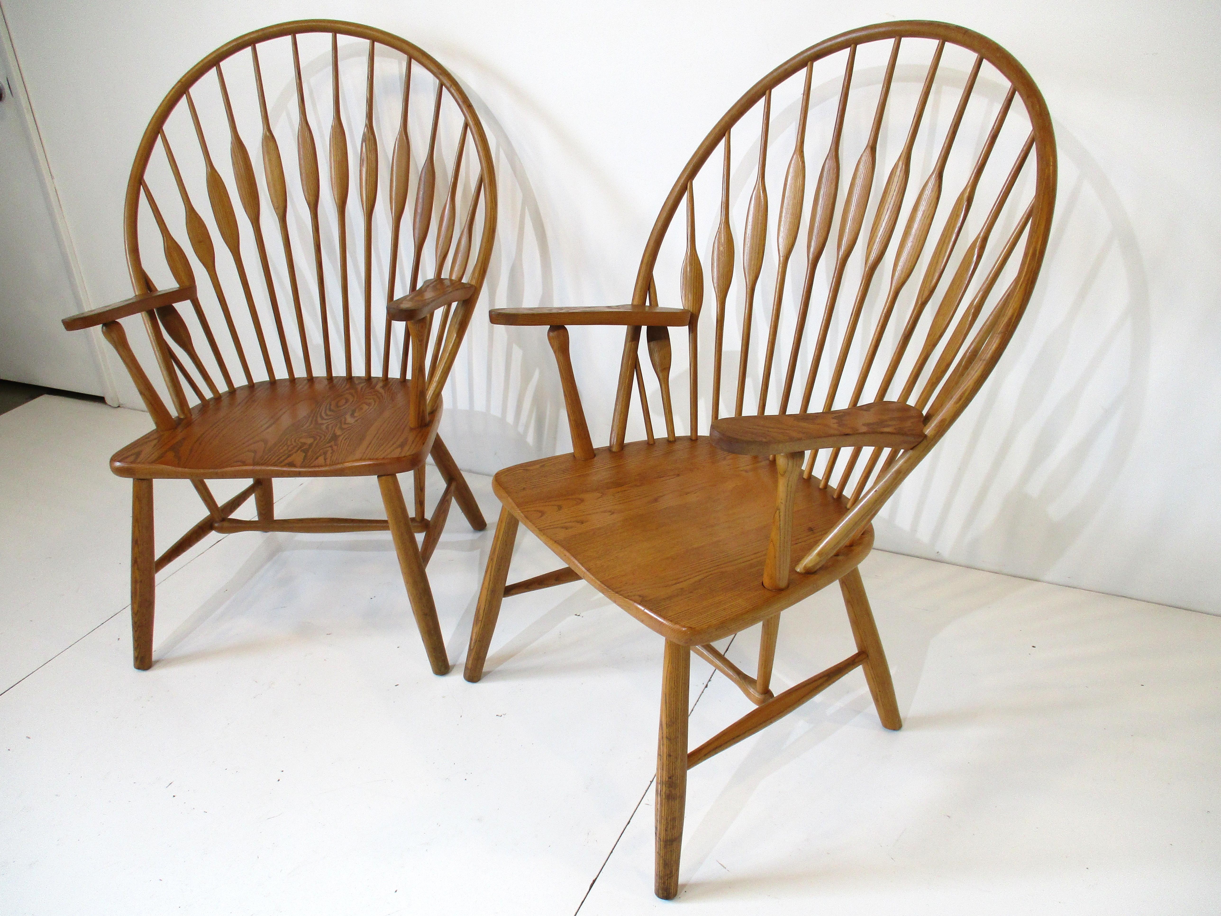 A pair of handcrafted wooden Peacock chairs with curved back, sculptural spindles and legs with arms. Designed in the manner of Danish modernist Hans J. Wegner and his model JH 550 chairs. The chairs are super comfortable and will fit with many