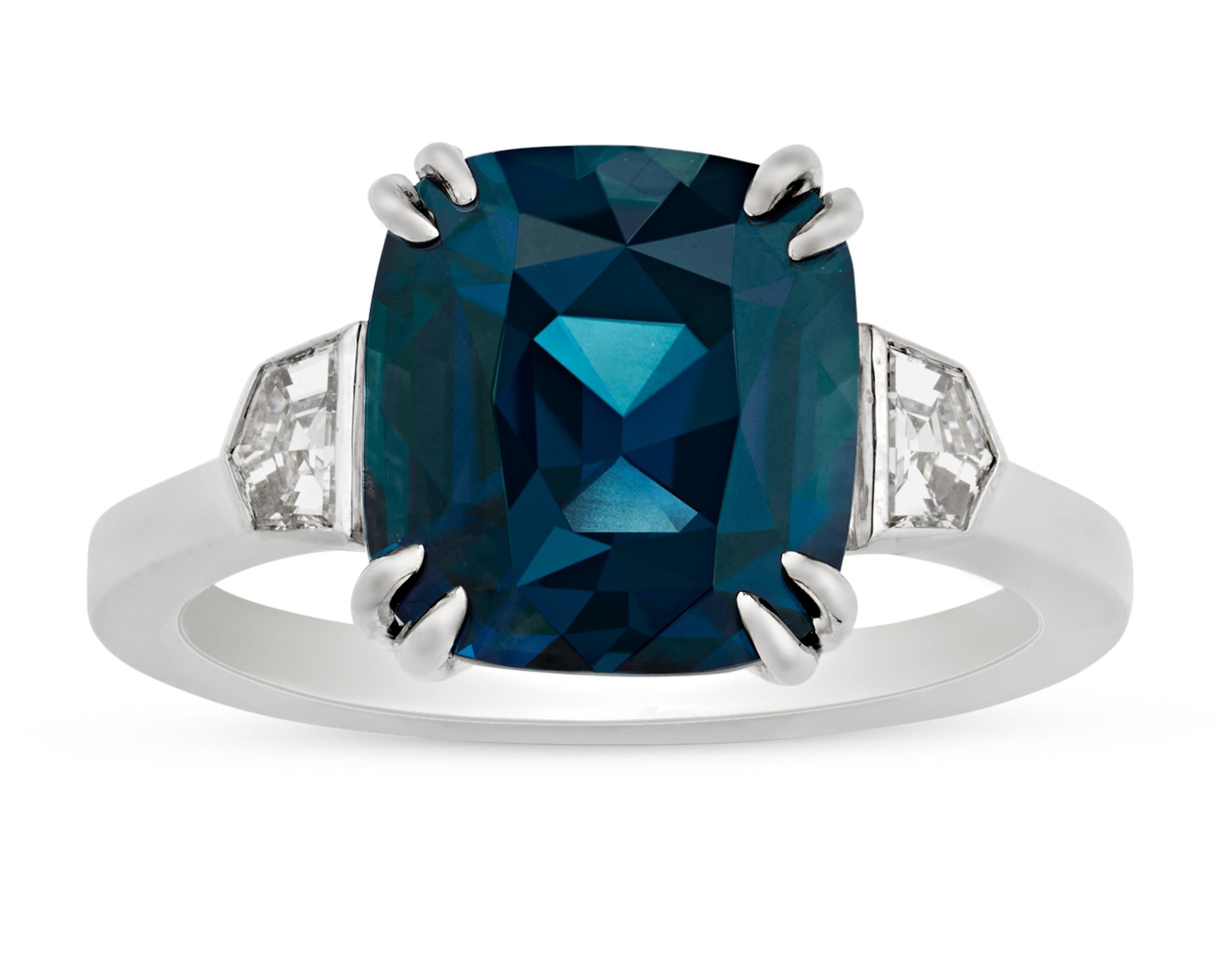 A peacock-blue sapphire weighing 5.21 carats centers this dazzling ring. With its striking color, stunning beauty and large size, the brilliant step-cut gem displays amazing clarity and a highly saturated blue-gree hue. Its unique coloration is