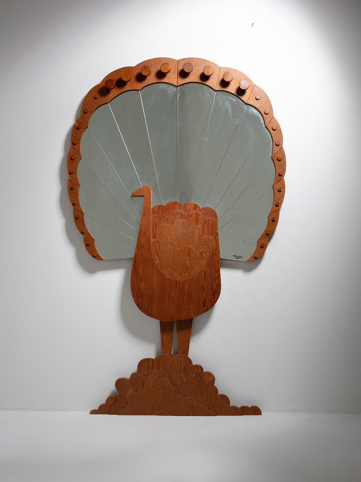 Seltener Spiegel in Pfauenform, hergestellt von Pallucco, Rom.
Sperrholzrahmen mit Spiegelplatten. Das Stück kann auch als Garderobe genutzt werden; im oberen Bereich befinden sich mehrere runde Holzhaken. 
