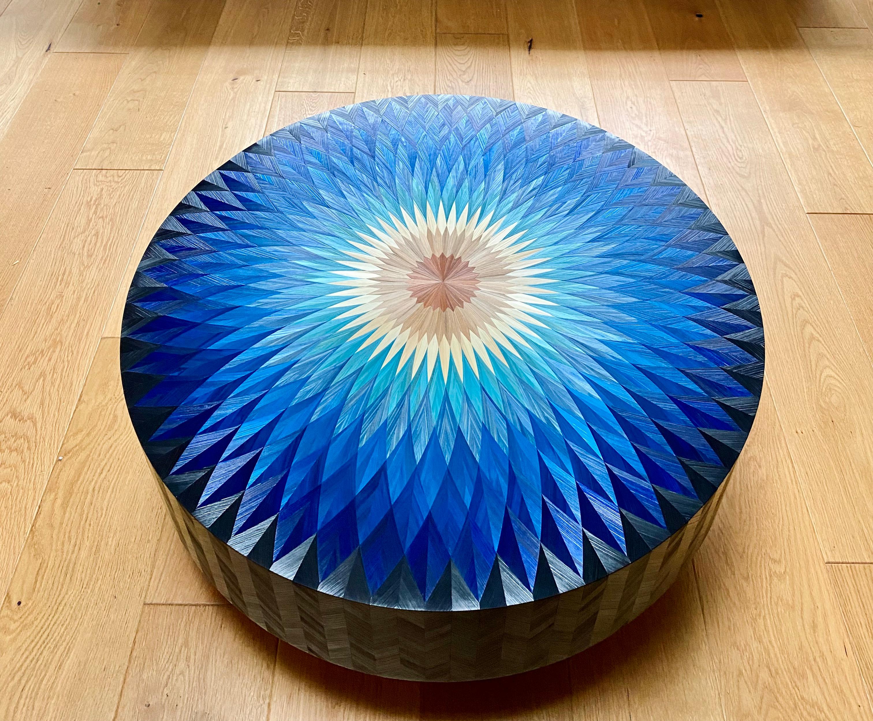 This coffee table represents a rosette in shades of blue. The solar and luminous center fades towards blue then black. The reflections are endless on this plateau and the edges are entirely inlaid with rye straw.

I wanted to put this rosette as if