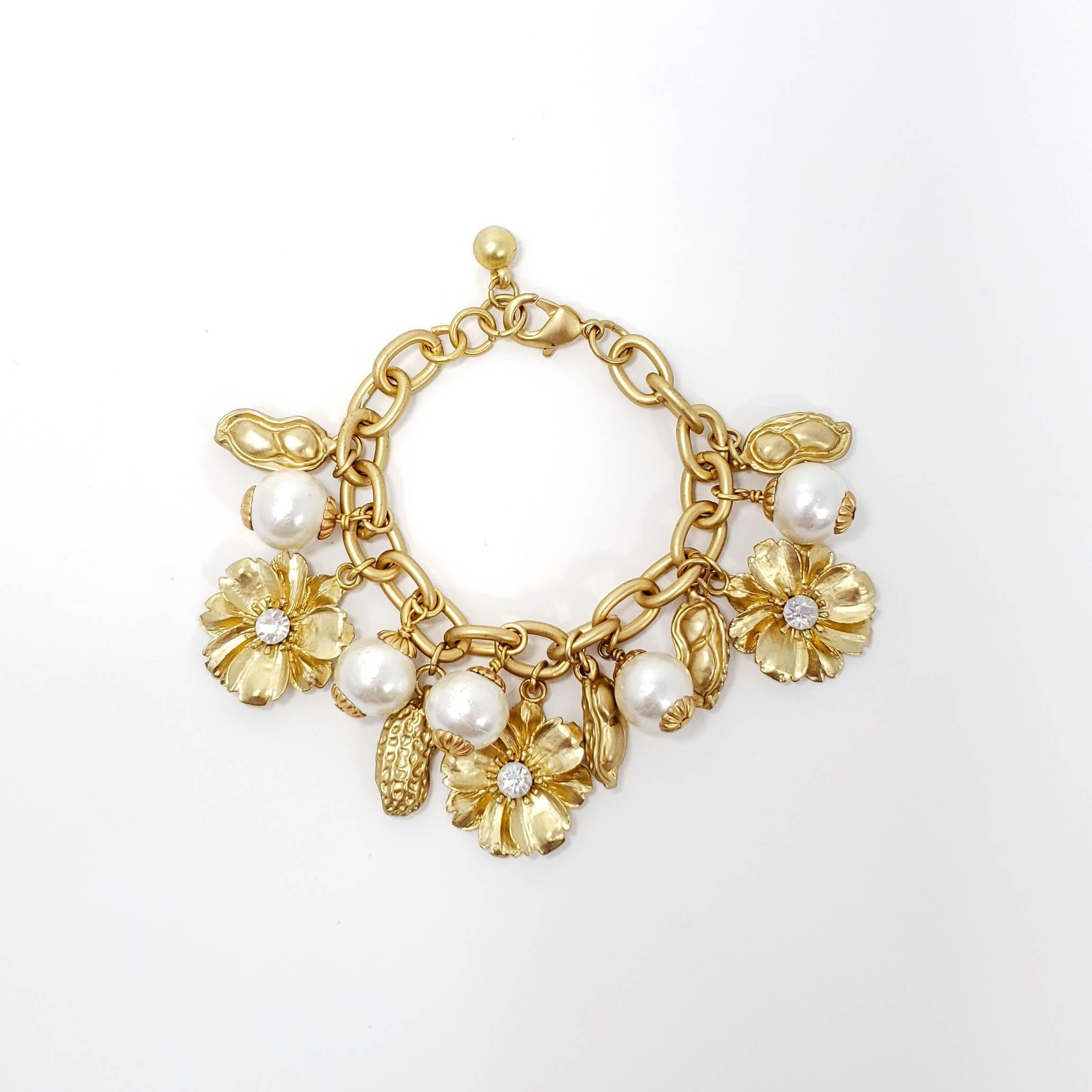 Charm chain bracelet in gold tone, with clusters of peanut, flower, and faux white pearl charms.

Excellent condition. Estimated production - mid to late 1900s.

Charms approx 1.5cm in length each.

Bracelet length: 7 to 8 in / 18 to 20 cm, includes