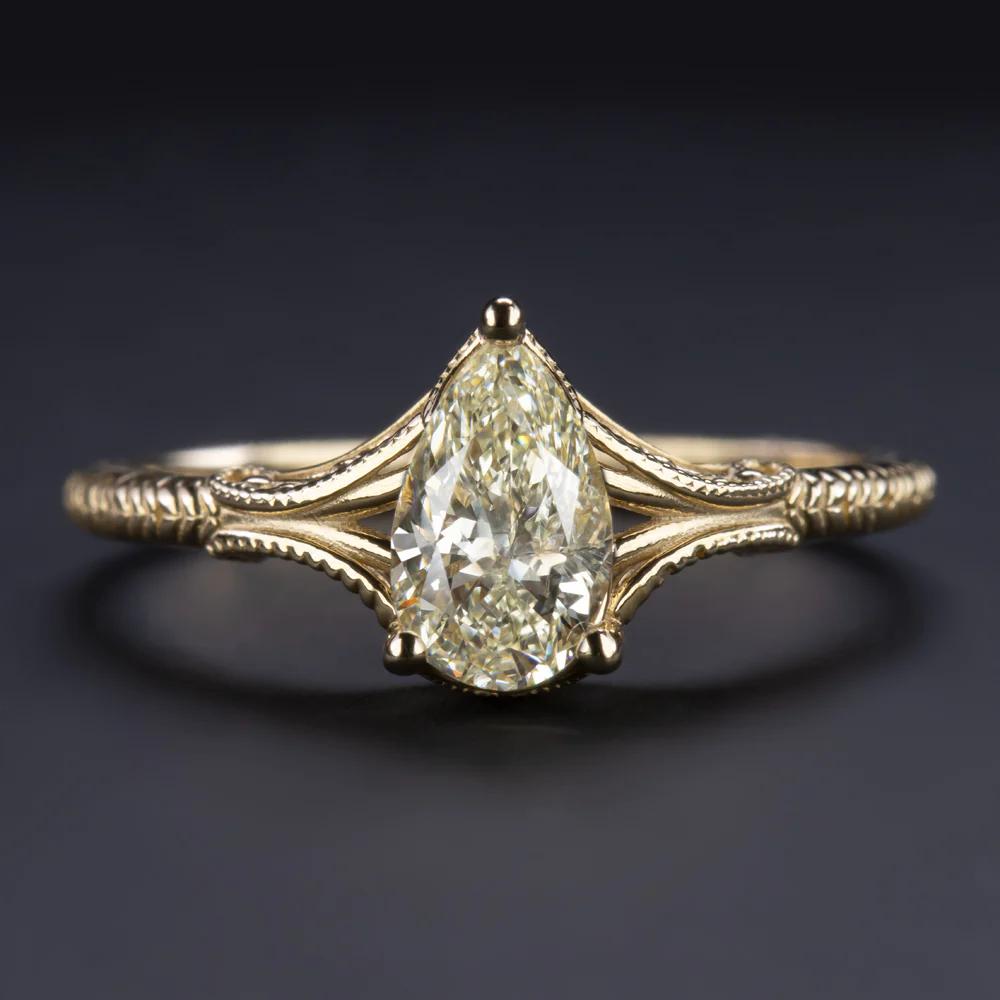 Engagement ring features a 0.73 carat pear cut natural diamond set in elegant and classic design.
The setting is richly textured with an intricate engraving, curling filigree, and very fine milgrain.
The main diamond is graded O-P for color and