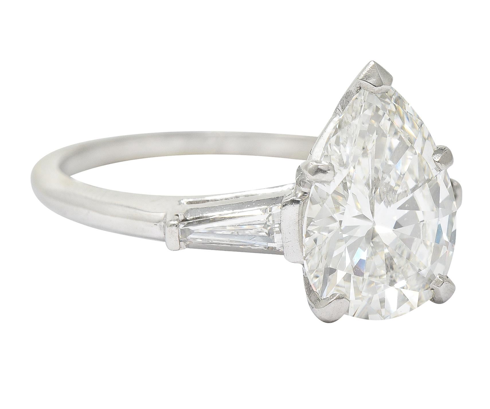 Engagement ring centers a pear cut diamond weighing 3.16 carats total - I color with VS2 clarity. Prong set in basket and flanked by cathedral shoulders with bar set tapered baguette cut diamonds. Weighing approximately 0.40 carat total - I color